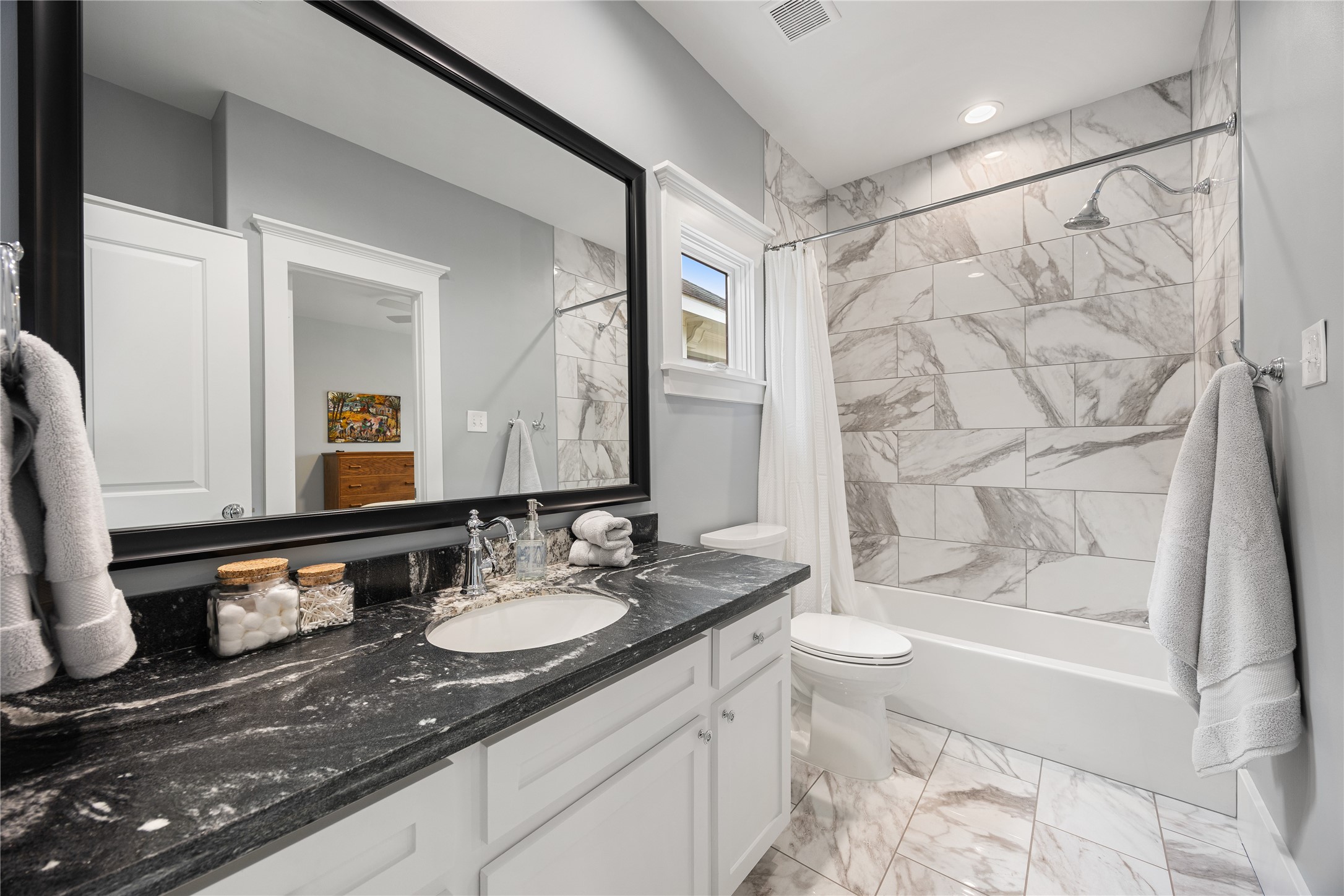 Remodeled secondary bathroom features updated tile, vanity finishes & a tub/shower combination.