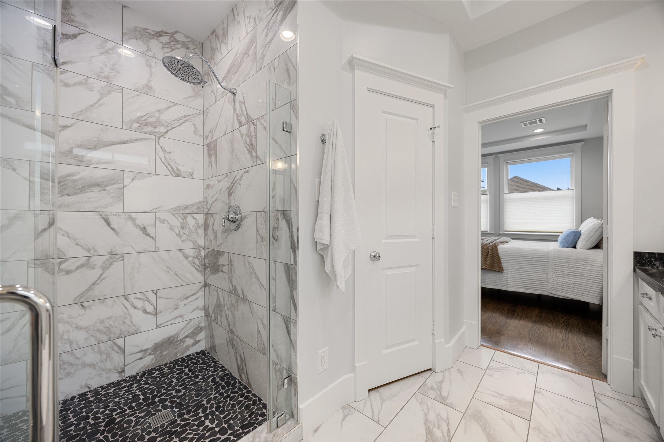 Beautifully updated primary shower features marble-look tile, a built-in niche & glass enclosure.