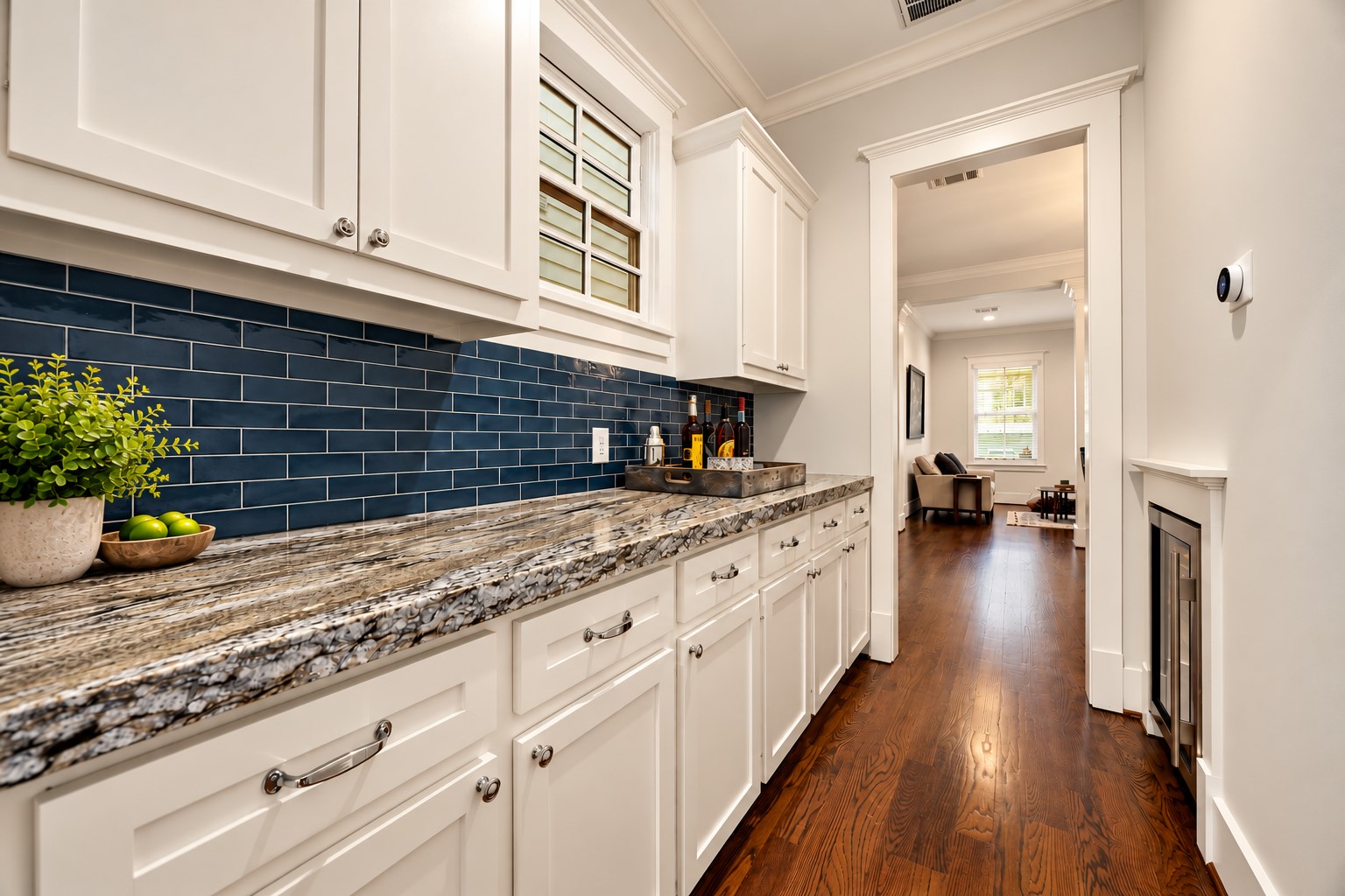 Butlers pantry features extensive cabinetry, leathered Blue Dune granite countertops, striking navy subway tile backsplash & a Sub-Zero wine coolerideal for entertaining & additional storage.