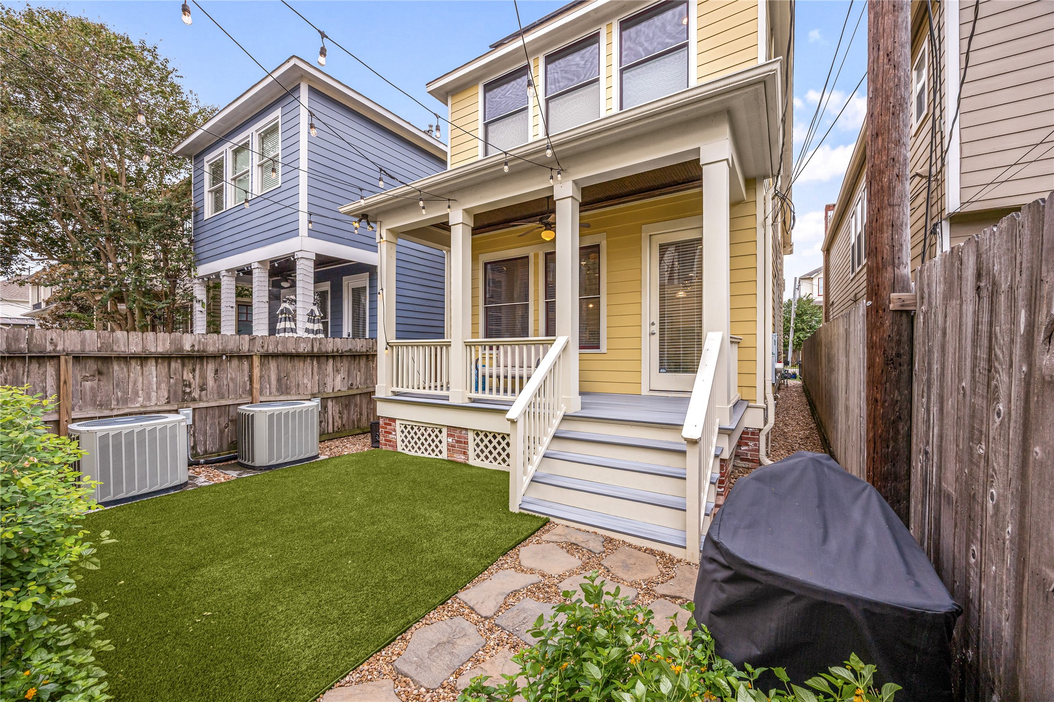 Another view of the Private fenced backyard features low-maintenance artificial turf, mature landscaping & inviting outdoor living spaces.