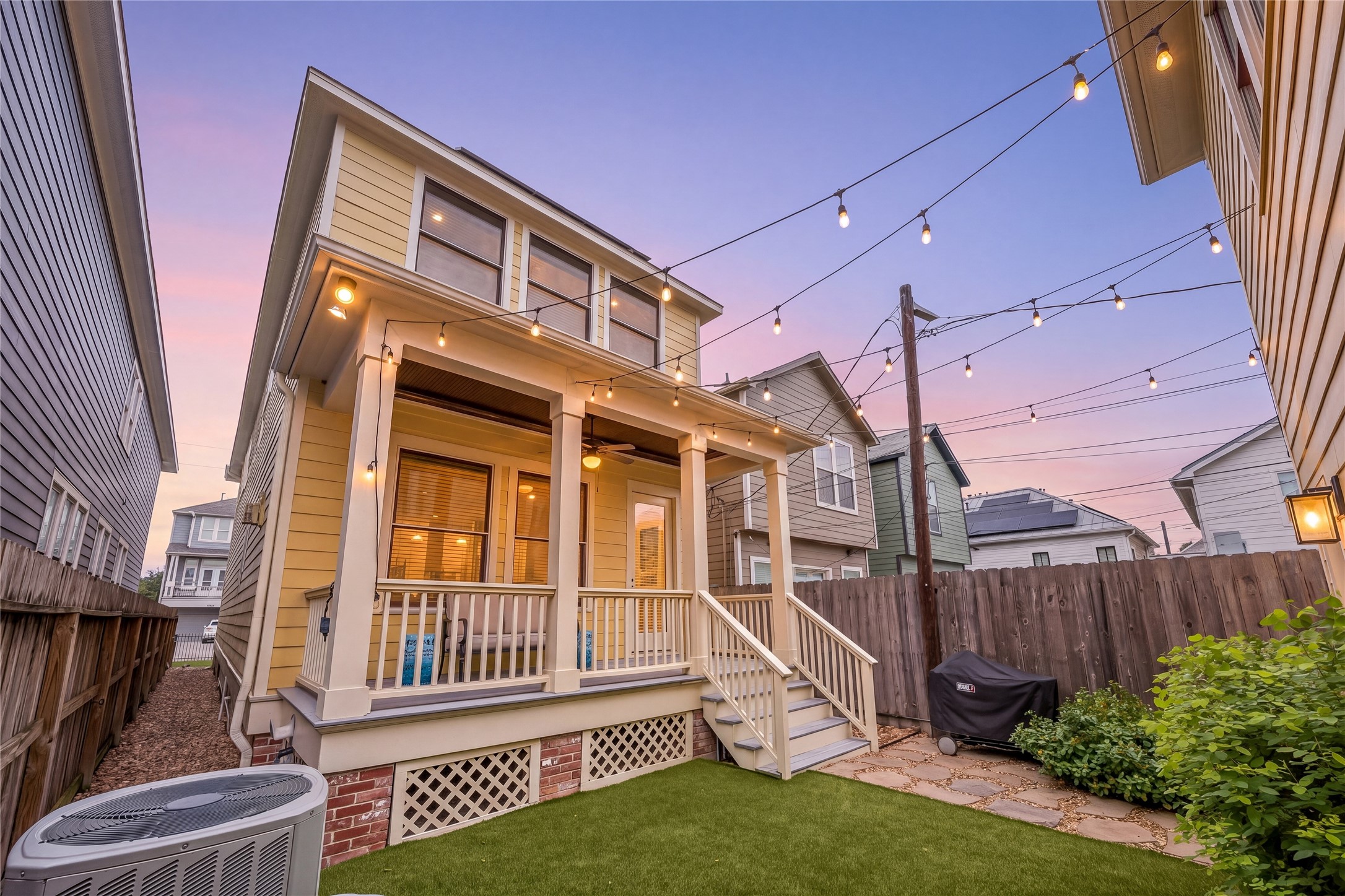 Beautifully illuminated exterior highlights the home's relaxing back porch, architectural details & charming backyard