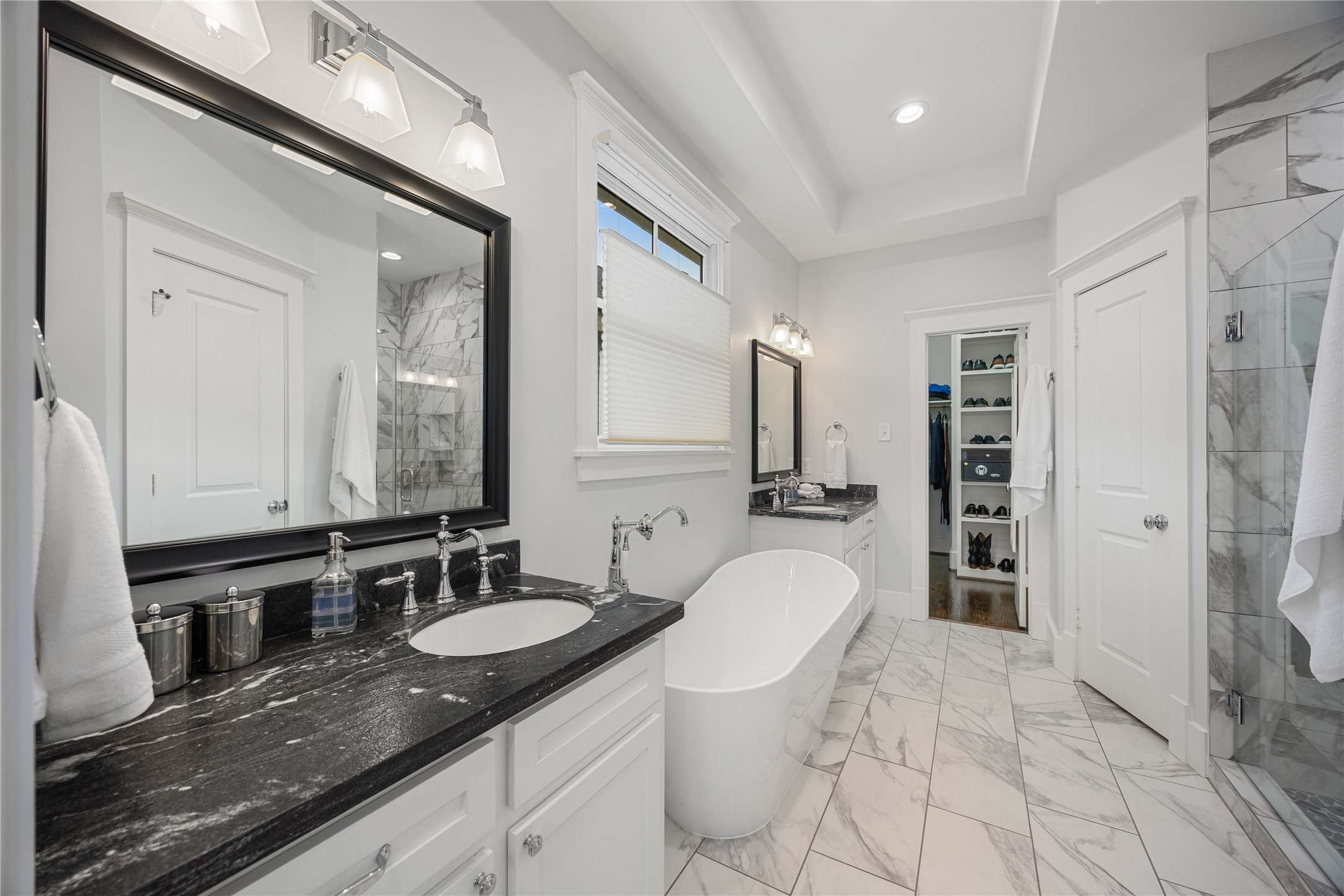 Remodeled primary bathroom features dual sinks, updated soaking tub and tile throughout, and elegant timeless finishes.
