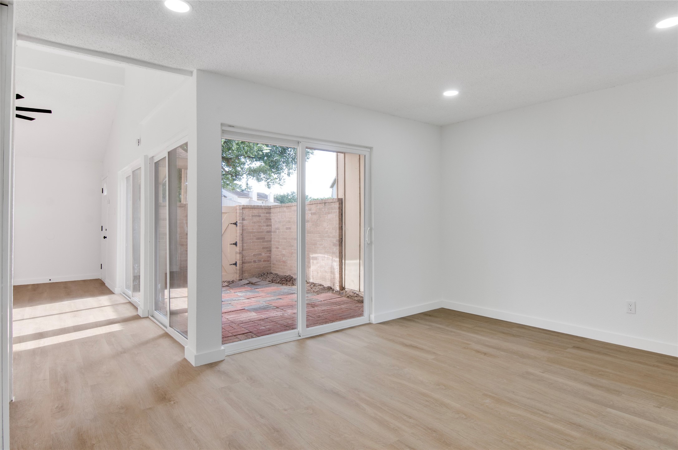 Bright and airy living space featuring sleek wood flooring, recessed lighting, and large sliding glass doors that open to a private patio.