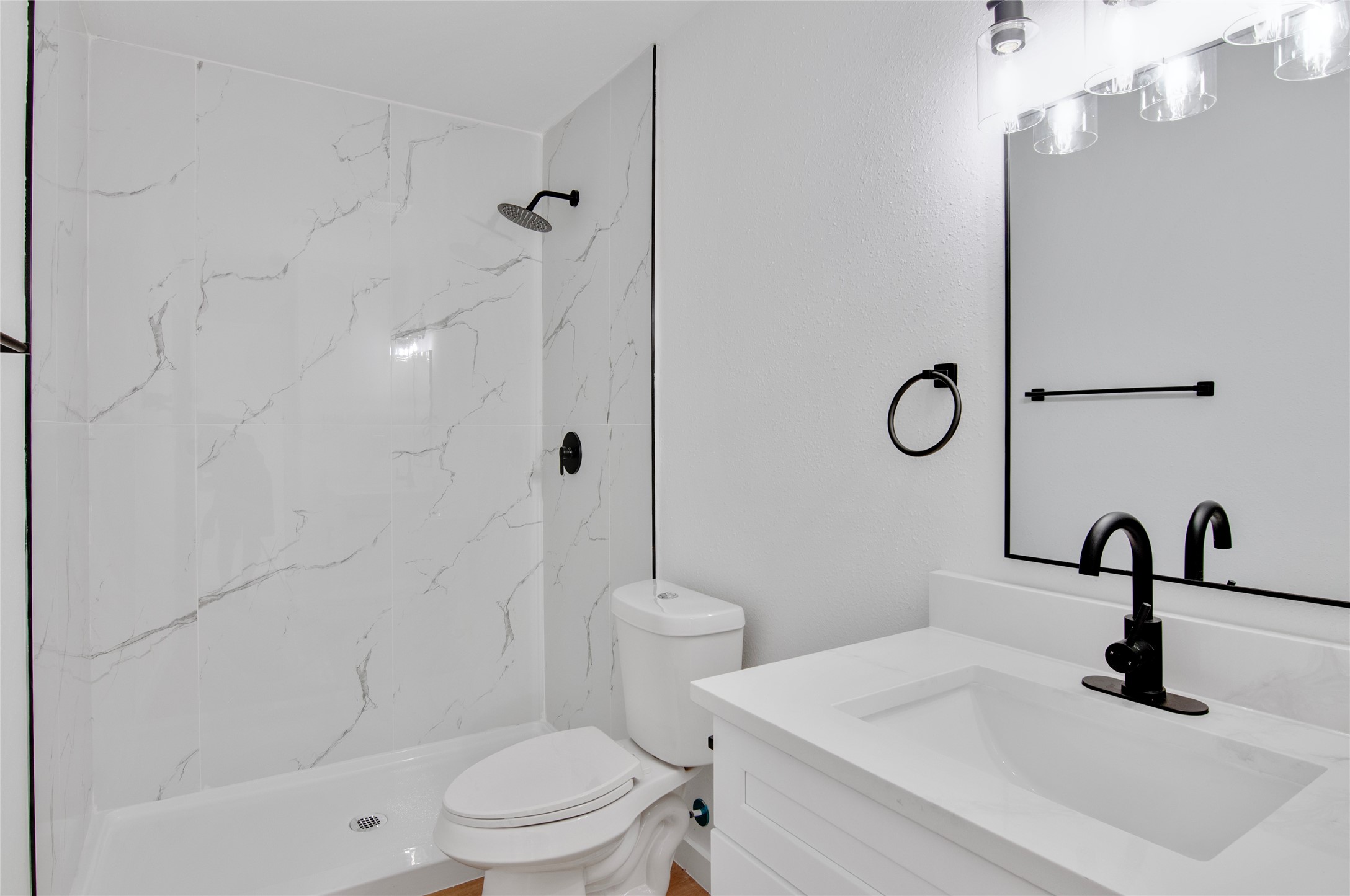 Sleek and modern bathroom featuring white marble tile, a spacious shower, and elegant black fixtures for a stylish touch.