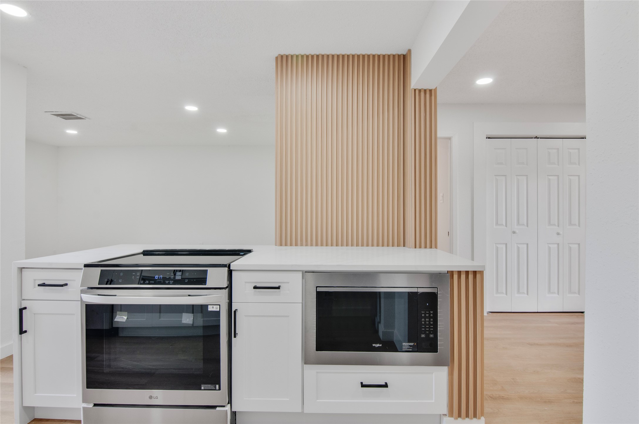 Modern kitchen featuring new stainless steel appliances, a stylish waterfall island, and elegant wood accents.