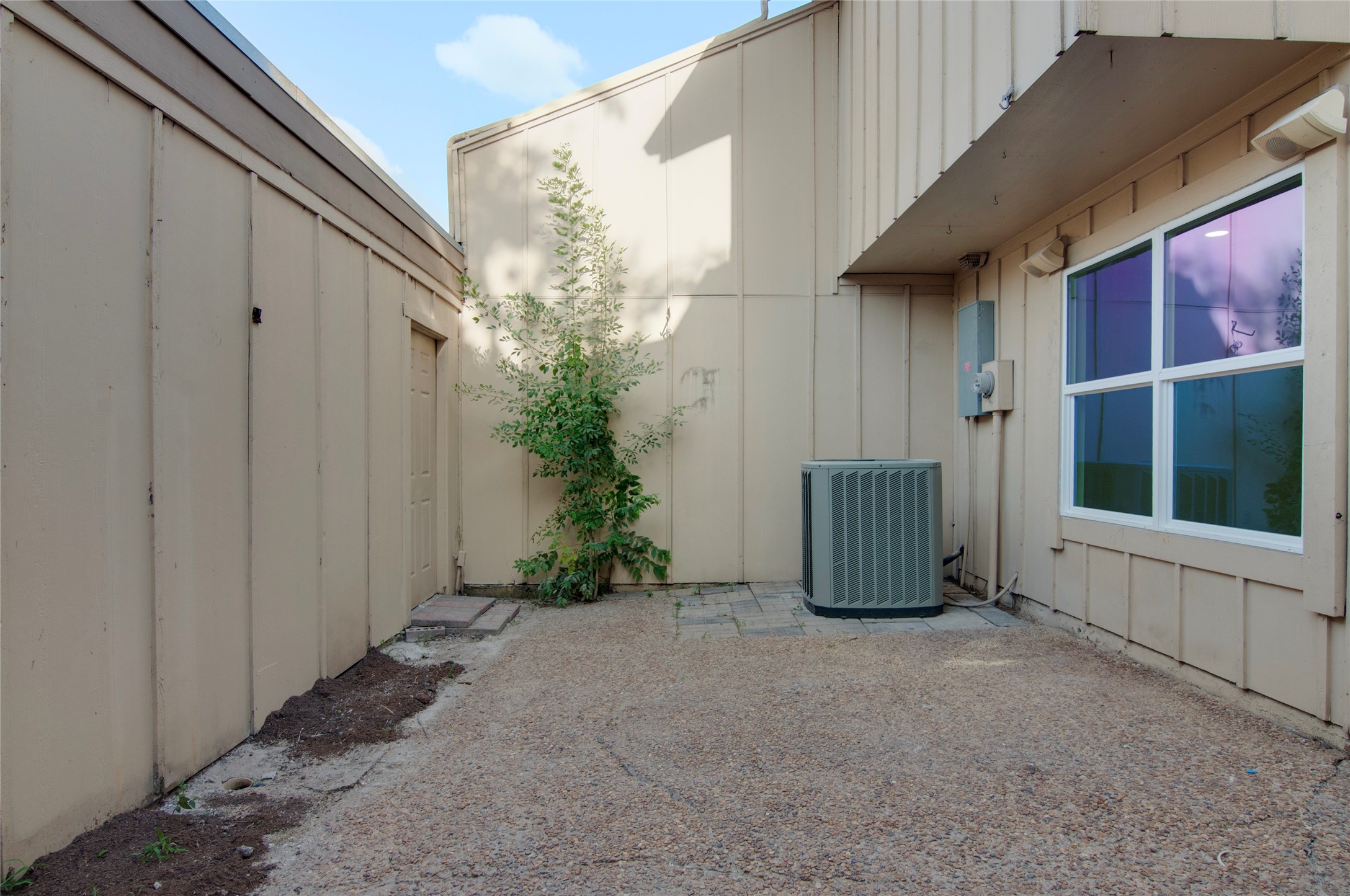 A private outdoor space with a clean pebble-finished patio, ideal for storage or a small garden area, featuring a convenient exterior utility unit.