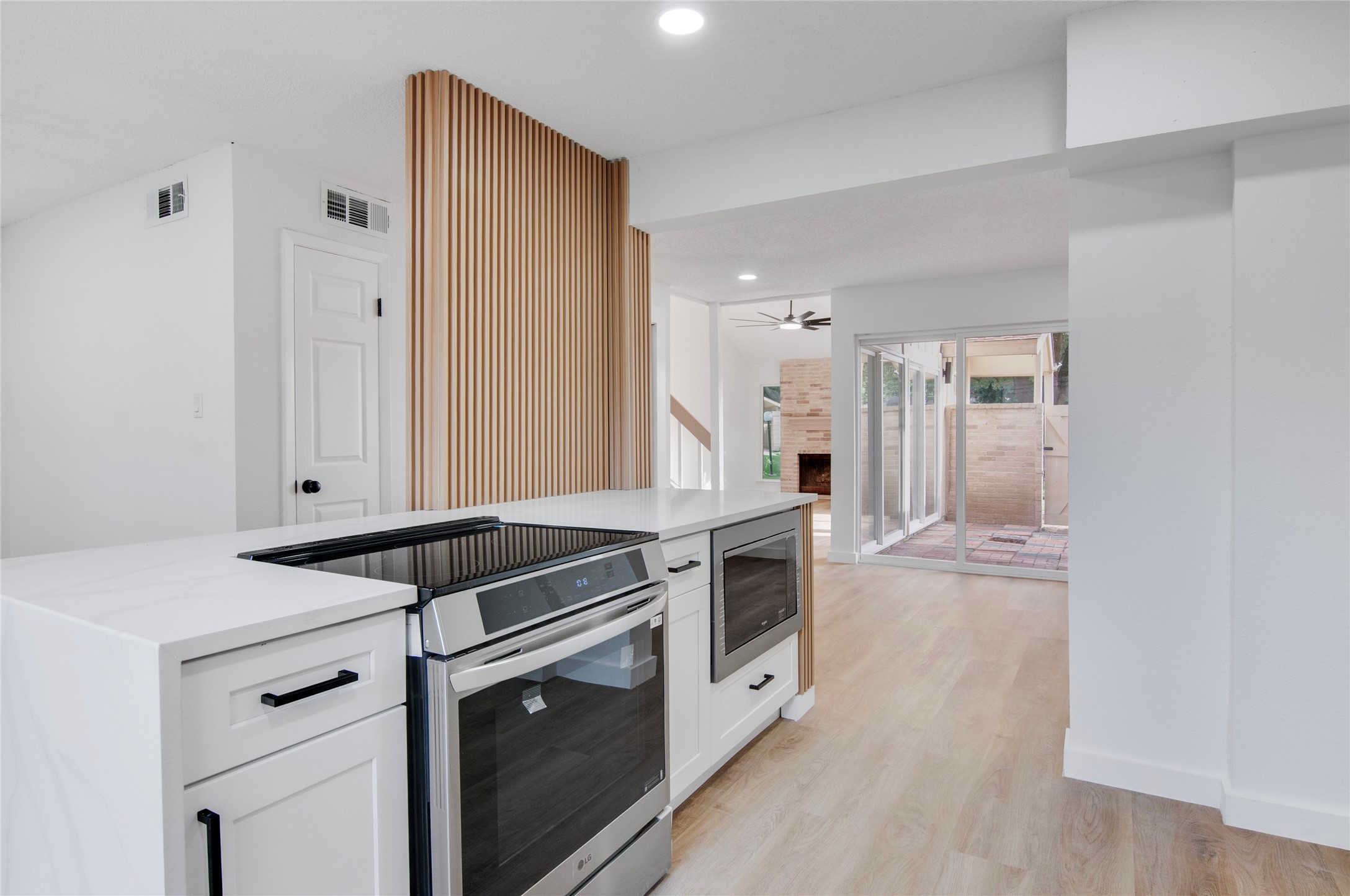 Modern kitchen with sleek appliances and a stylish island, seamlessly flowing into a bright living area with sliding glass doors leading to a cozy patio.
