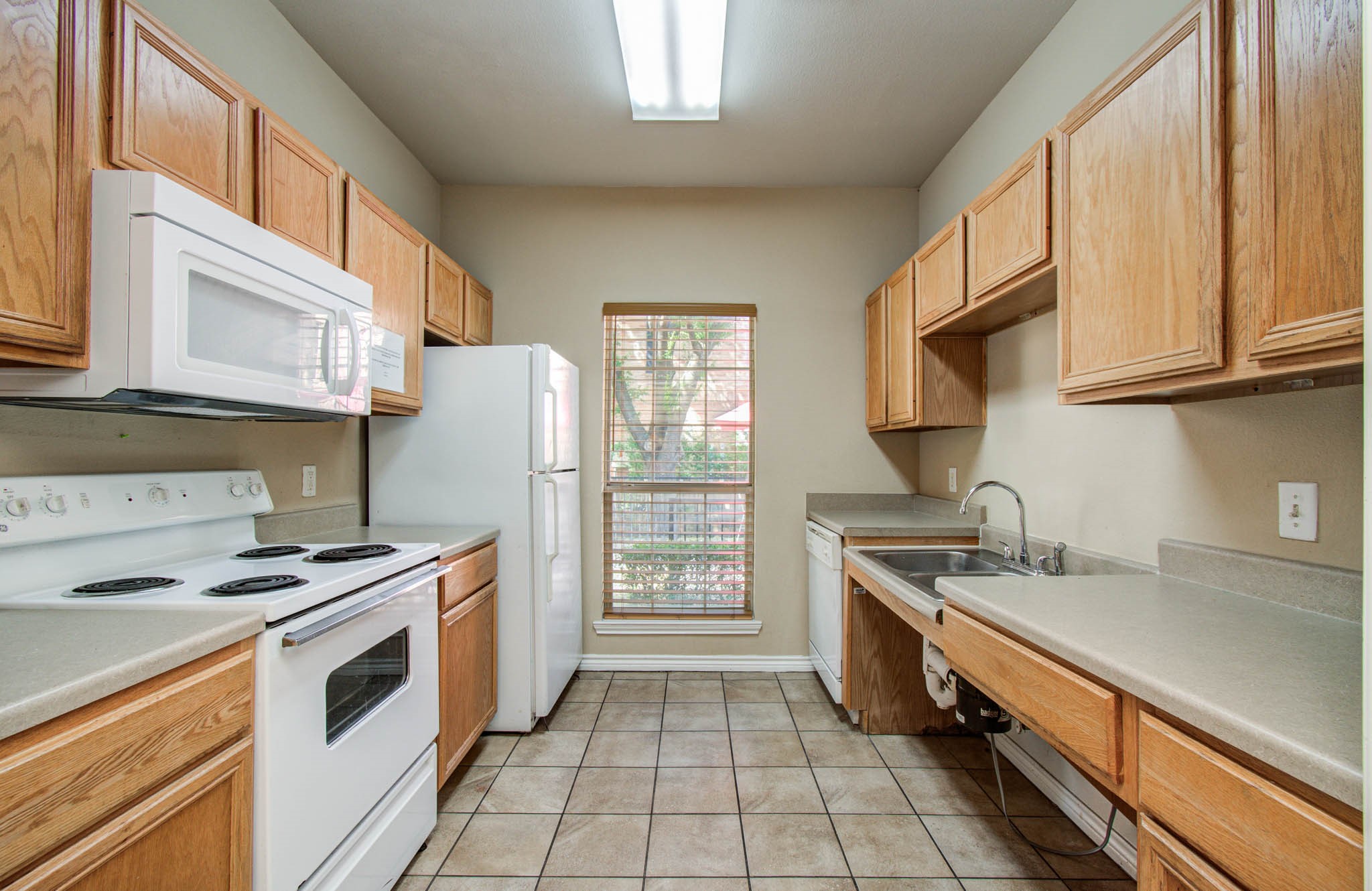 Clubhouse kitchen is fully equipped for entertaining with wooden cabinetry, essential appliances: stove, microwave, refrigerator, and dishwasher.