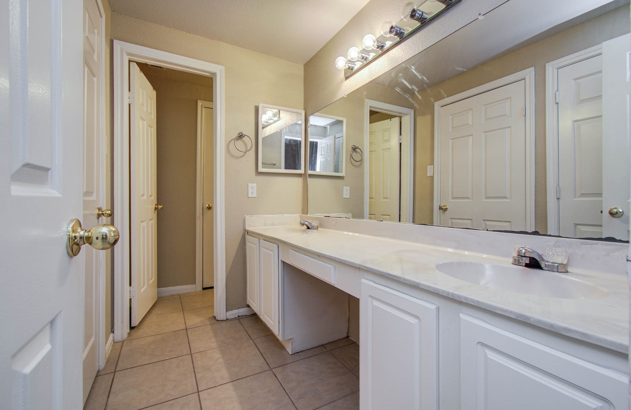 Bathroom features dual sinks, large mirror, and ample cabinet space.