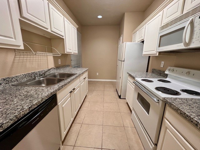 Kitchen features white cabinetry, granite countertops, and includes the refrigerator