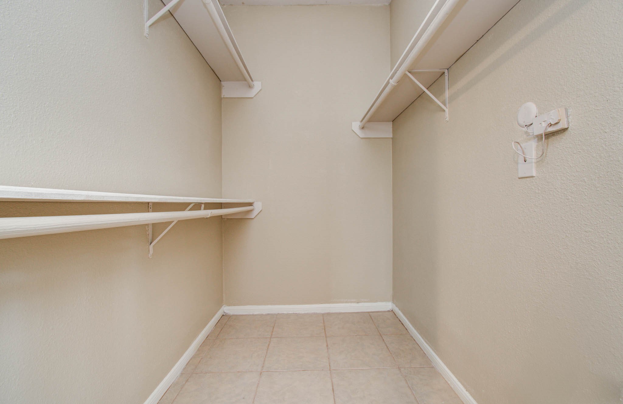 Bedroom features spacious walk-in closet with multiple shelves and hanging rods, offering ample storage space for clothing and accessories.