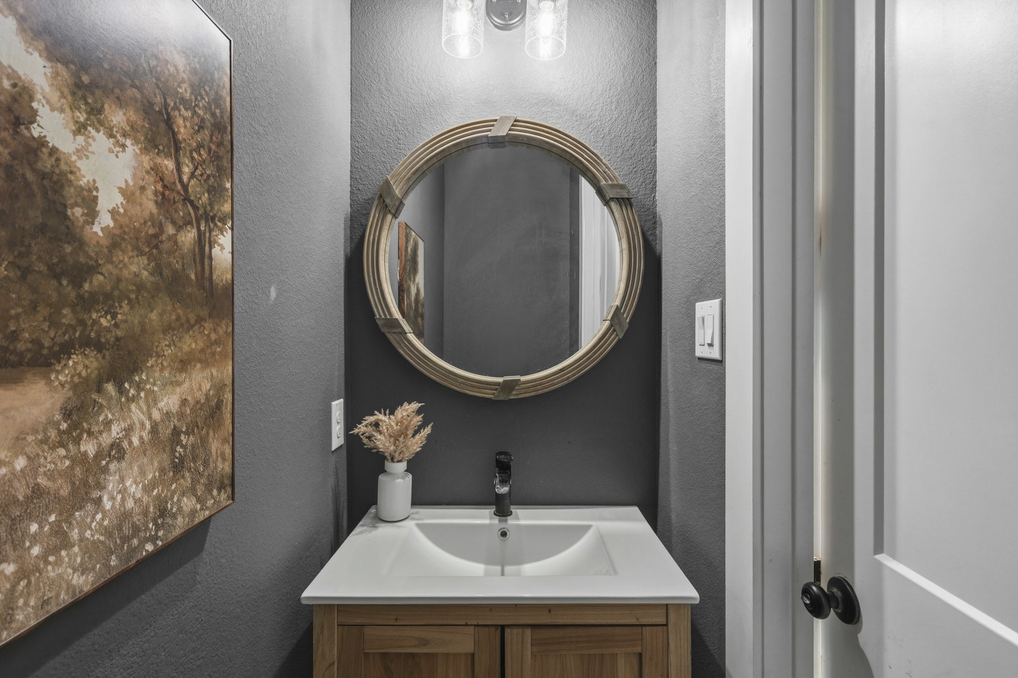 Conveniently located quietly off the Kitchen and Mud Room, the Powder Room is perfectly situated for guests and everyday use. This thoughtfully designed space features a pedestal sink, a custom framed mirror and designer paint.