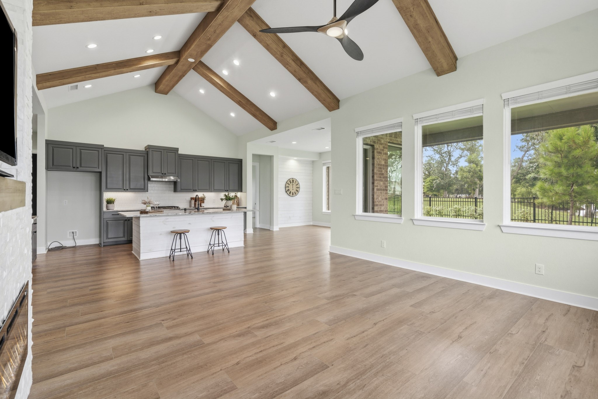 This view captures the grandeur of the space and shows how gracefully the Family Room flows to the Kitchen and how the walls of glass extend along the back of the entire home, flooding the space with natural light and breathtaking views.
