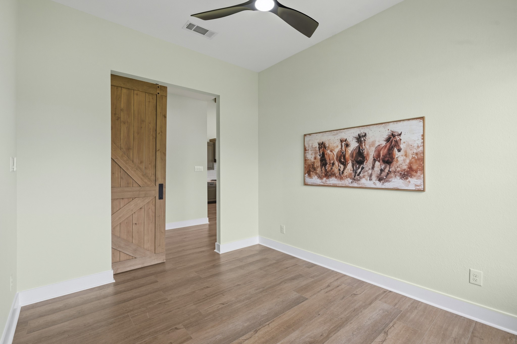The Study, located directly off the Foyer, is accessible through the rustic, yet stately barn door. Overhead, an upgraded 60-inch fan is an artful mix of black and champagne gold serving both as a stylish focal point and a functional enhancement, ensuring the room remains comfortably illuminated and well-circulated year-round.