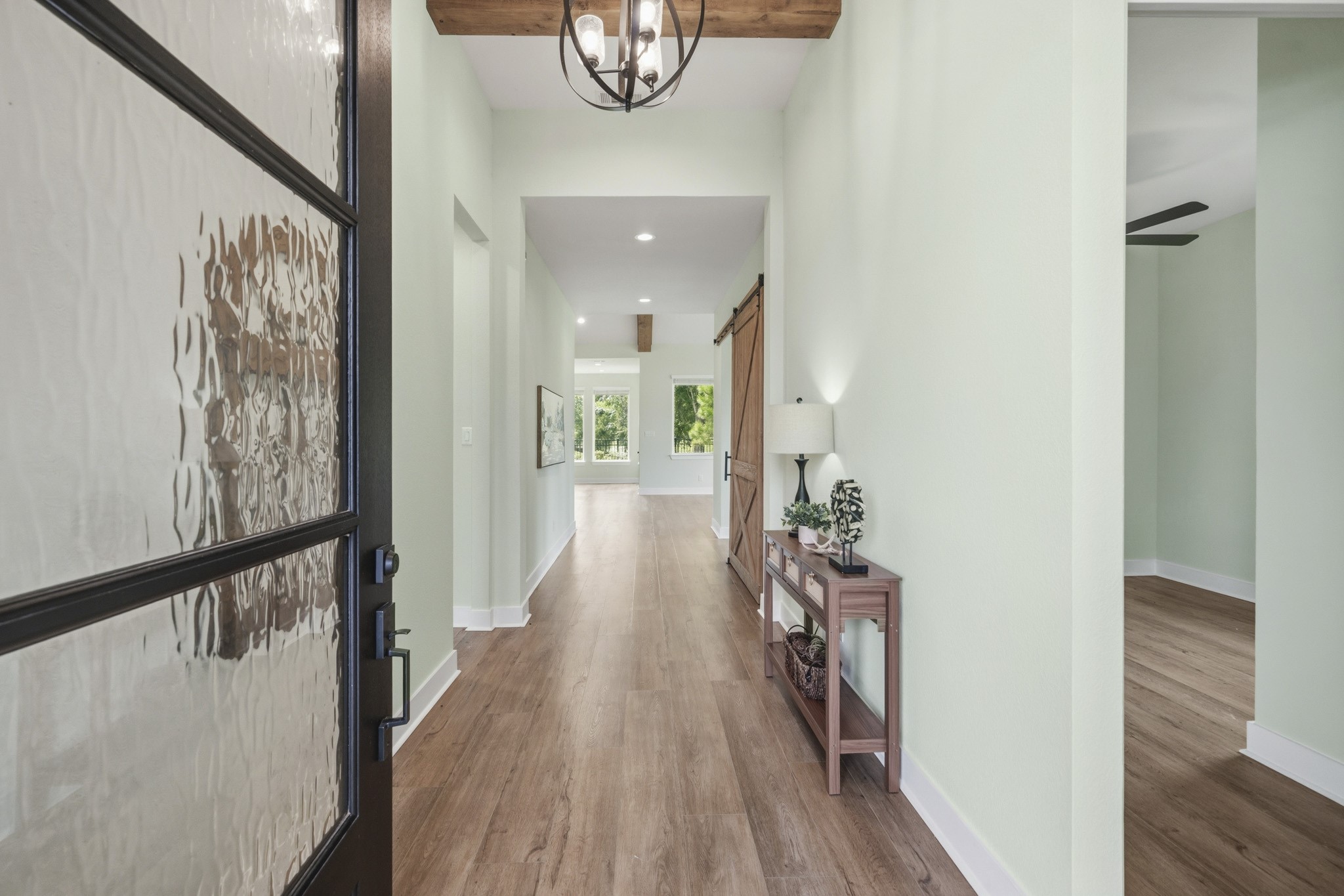 Upon entering the home, guests are greeted by soaring ceilings accented with rustic wood beams, a designer chandelier, upgraded LVP flooring, and a custom neutral color palette that creates an inviting sense of warmth, while the eye is drawn towards the incredible views from the Family Room.