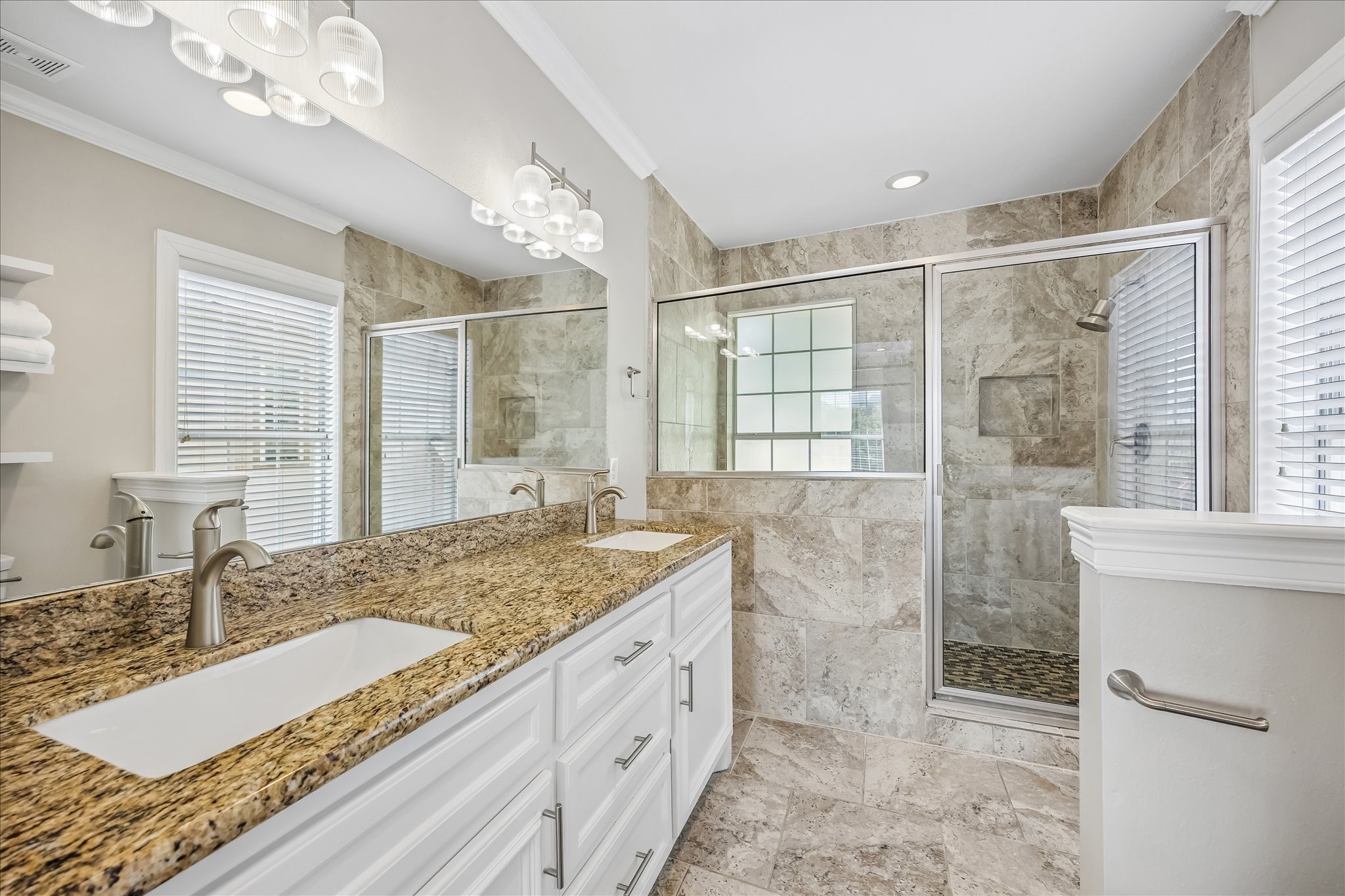 Primary bath features dual sinks, granite counters, generous cabinetry, and a large glass-enclosed shower.