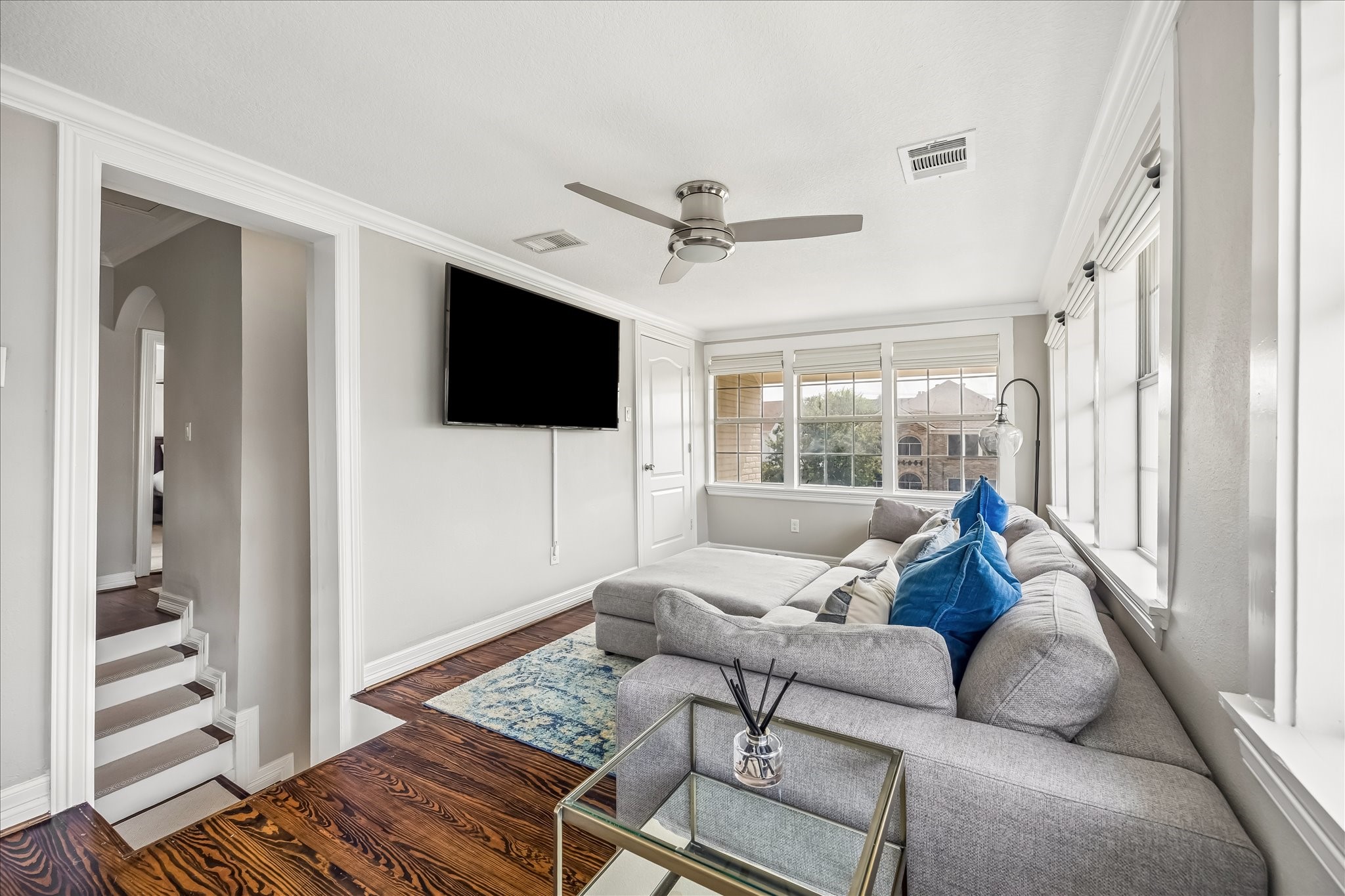 Upstairs family room creates a separate everyday living area, with windows on two sides, wood flooring, and room for a comfortable seating arrangement.