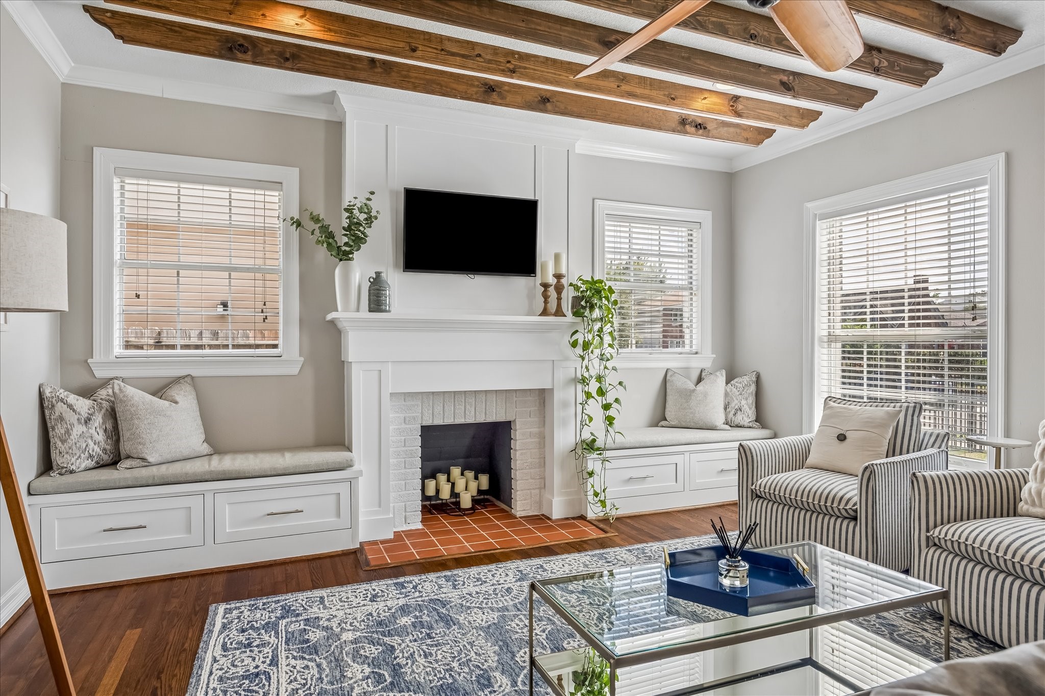 Exposed ceiling beams, a centered fireplace, and built-in window seating give the living room plenty of character, with cabinetry and benches upgraded in 2022.