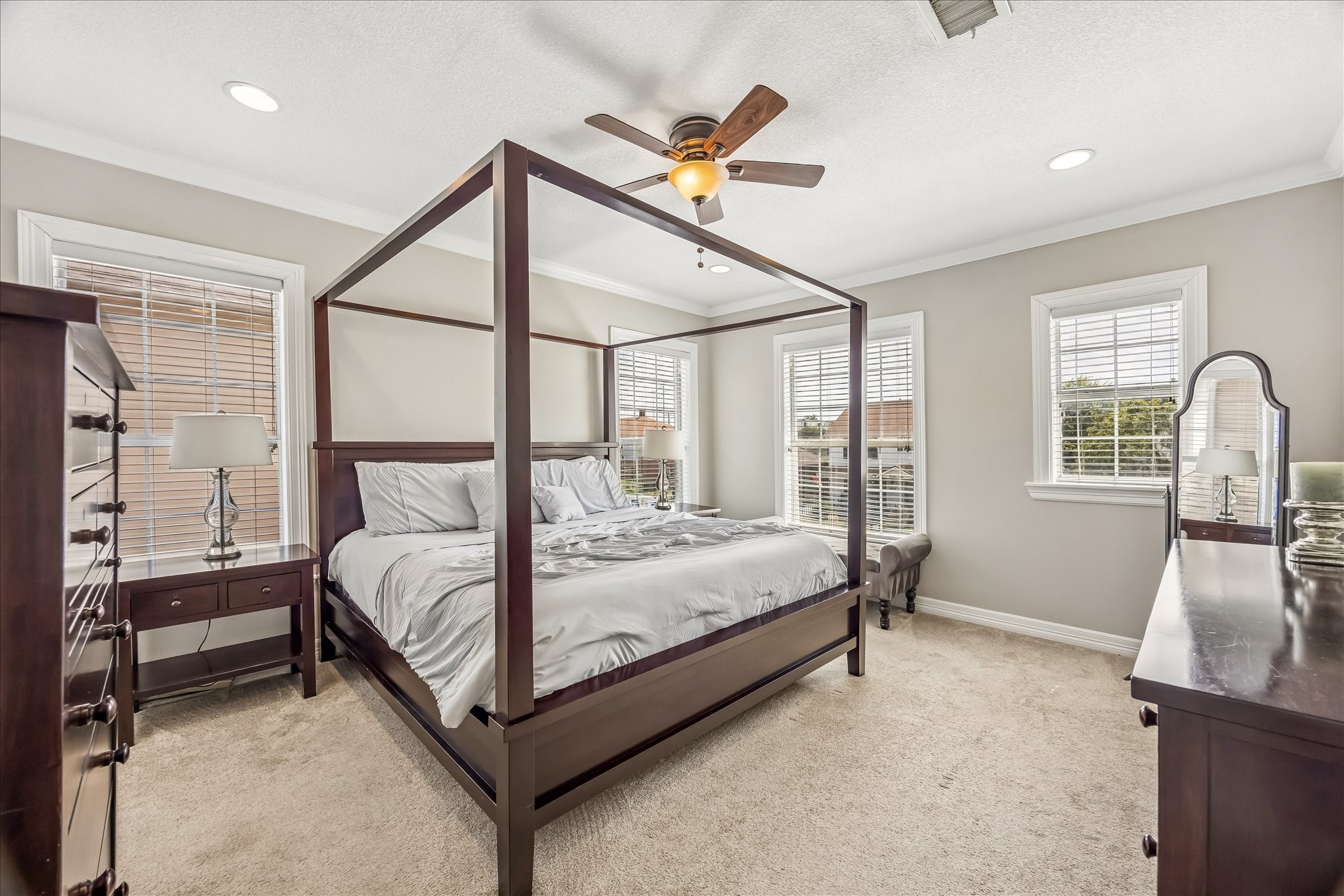 Spacious primary suite offers soft natural light, room for substantial furniture, and a ceiling fan overhead.