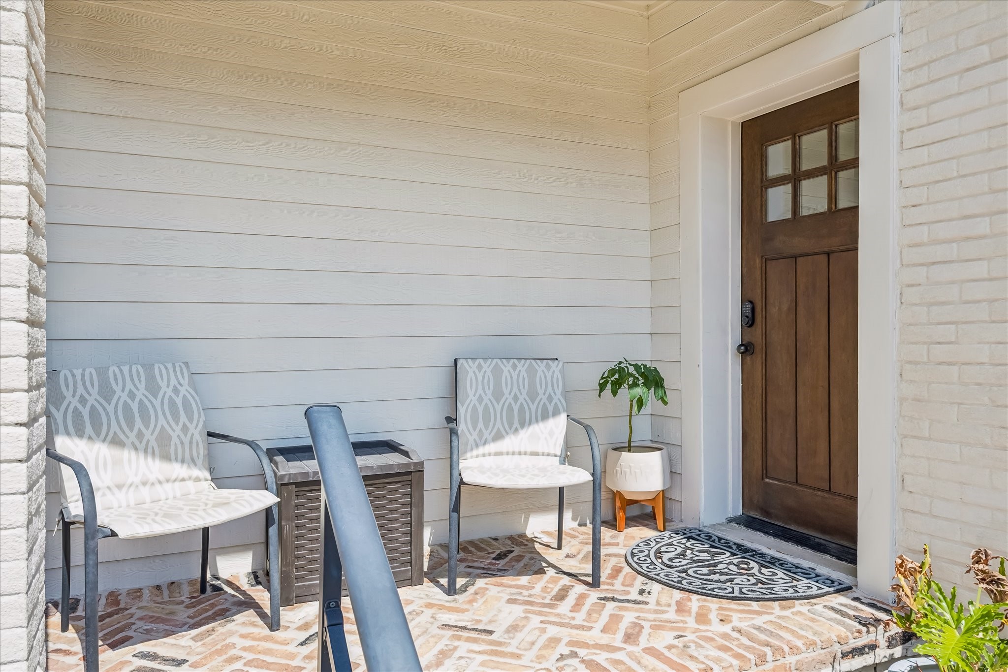 Covered porch is finished with brick detailing completed in 2019, creating a comfortable place to sit just outside the home.