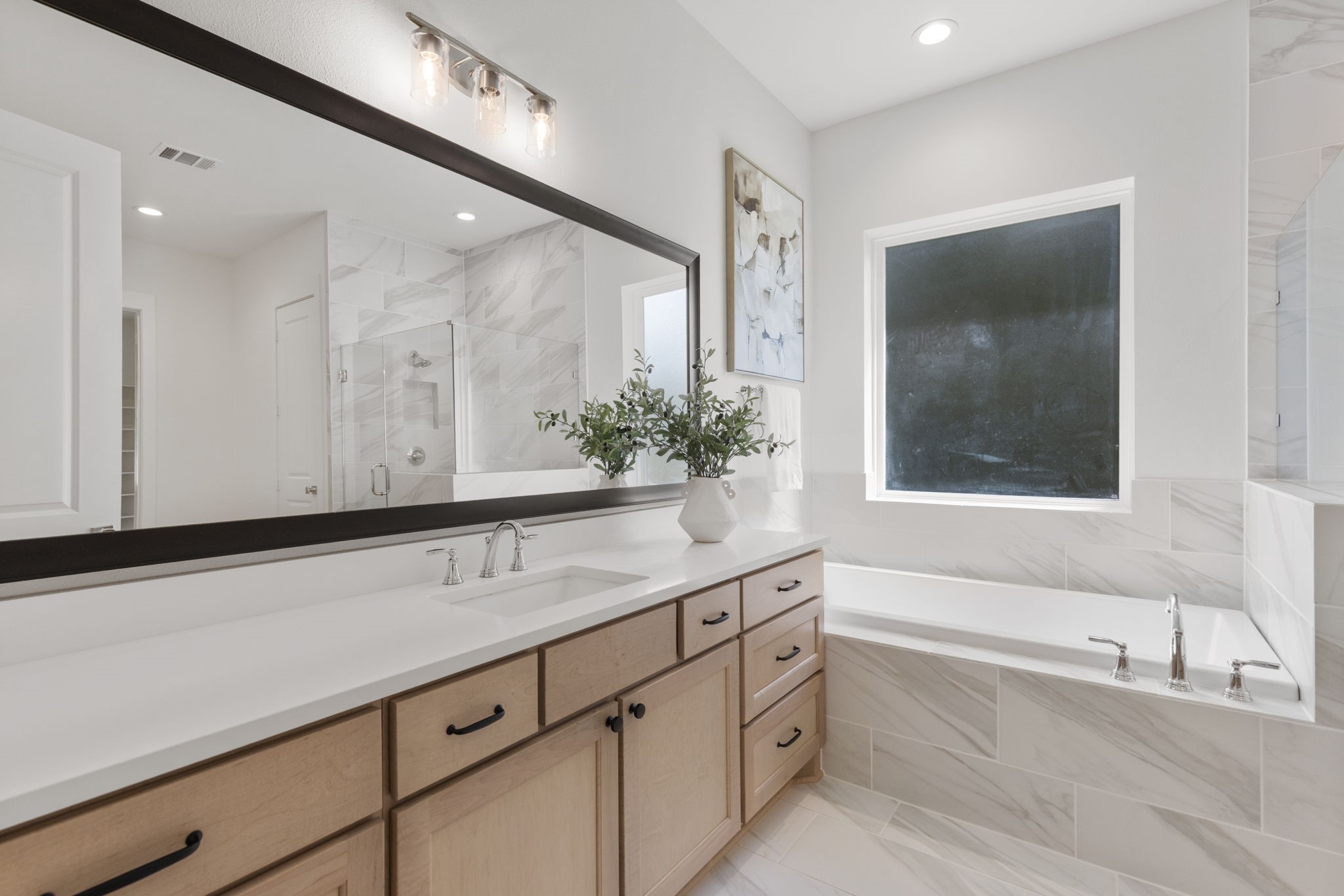 This modern soaking tub creates a spa-like retreat, perfectly positioned under a window to provide abundant natural light throughout.