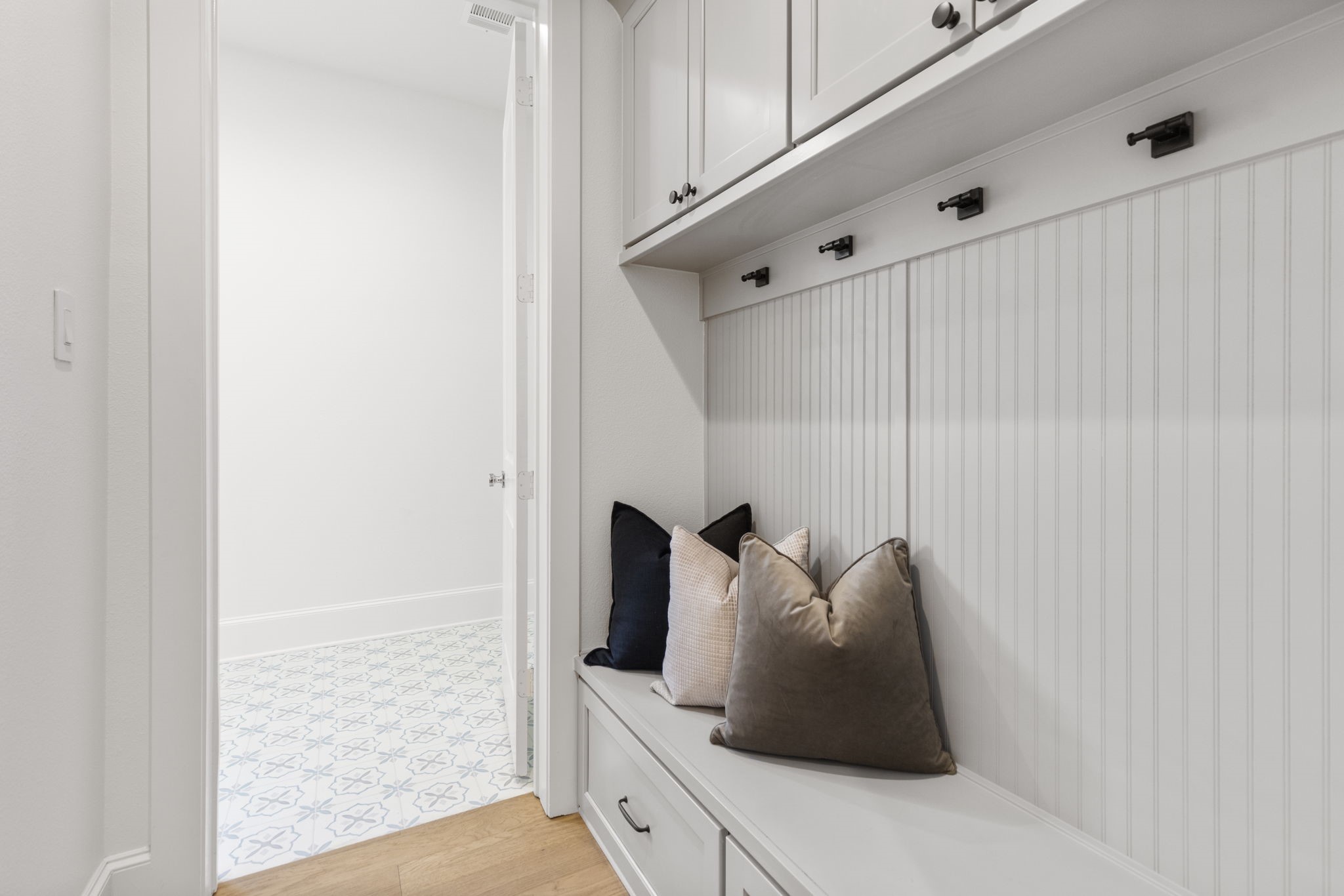 Custom mudroom drop zone featuring integrated bench seating with deep storage drawers for shoes and gear, complemented by overhead cabinetry for additional organization.