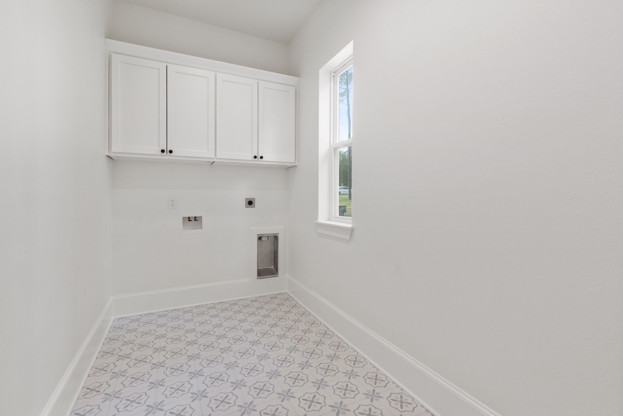 The laundry room has gorgeous tile floors, custom cabinets, and a window for views and natural lighting.