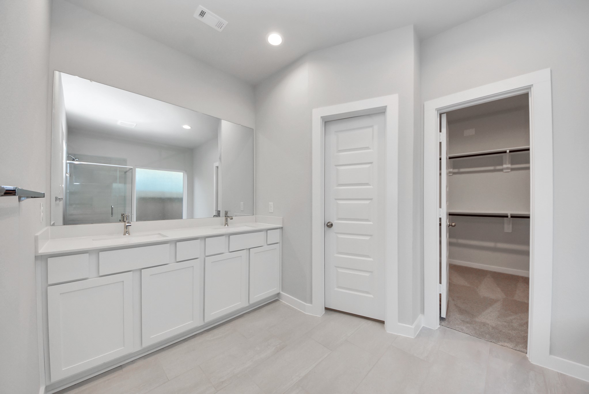 Elevate your daily routine at the elegant vanity, now equipped with double sinks, light countertops, modern hardware, and beautiful recessed lights.