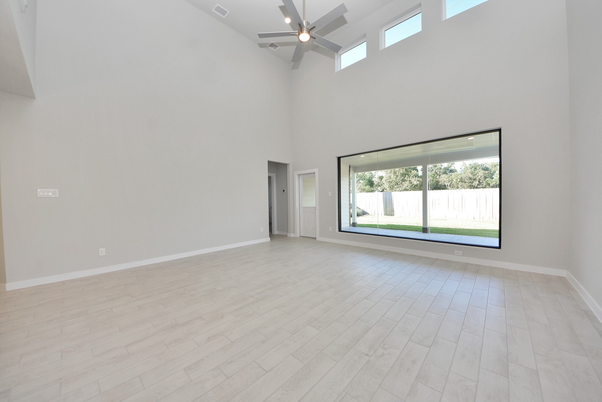 Welcome family and guests to your charming living room! With its high ceilings, recessed lighting, ceiling fan, custom paint, beautiful flooring, and large windows that let in abundant natural light, this room is perfect for gatherings.