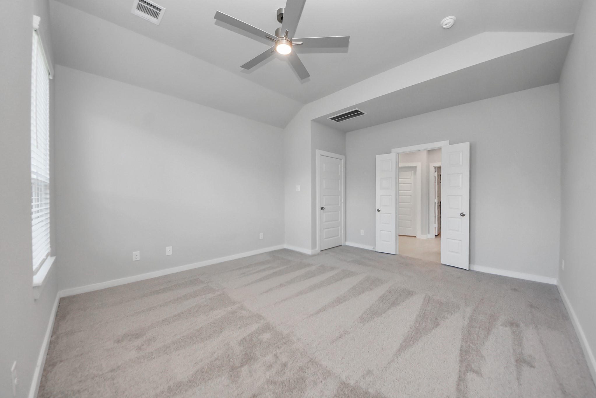 Escape and relax in the exquisite primary suite, a haven to unwind after a long day. The spacious room, located on first floor, boasts plush carpeting, soothing paint tones, high ceilings, and expansive windows adorned with privacy blinds.