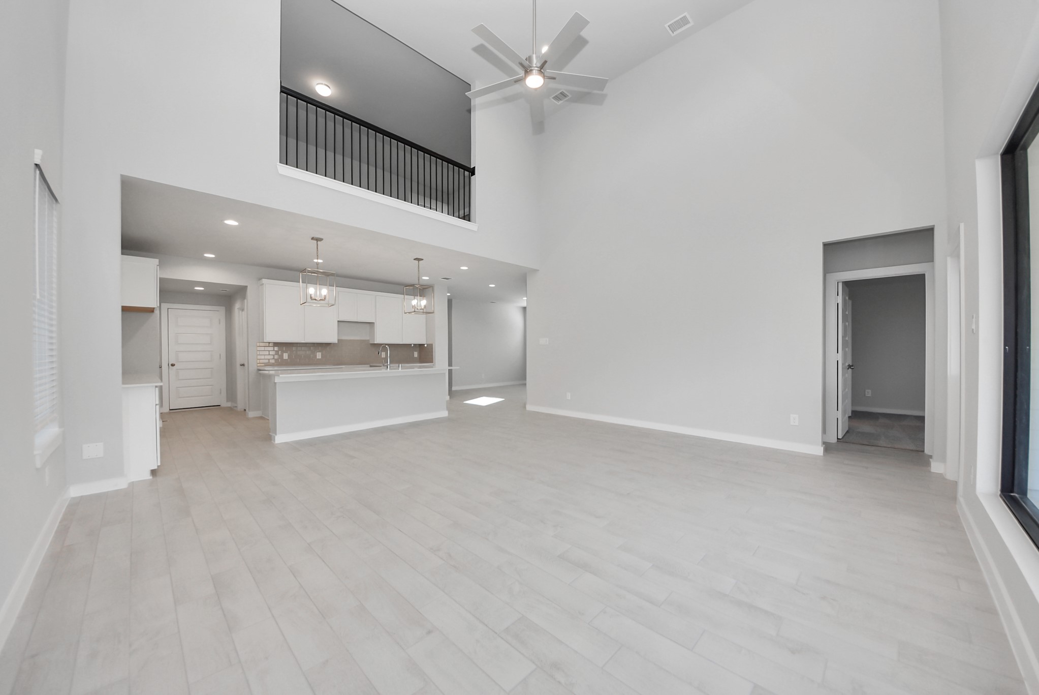 Relax and unwind in this inviting family room, illuminated by abundant natural light streaming in through tall windows, complemented by high ceilings and stunning flooring. Stay comfortable year-round with the gentle breeze from the ceiling fan, creating the perfect atmosphere for family gatherings.