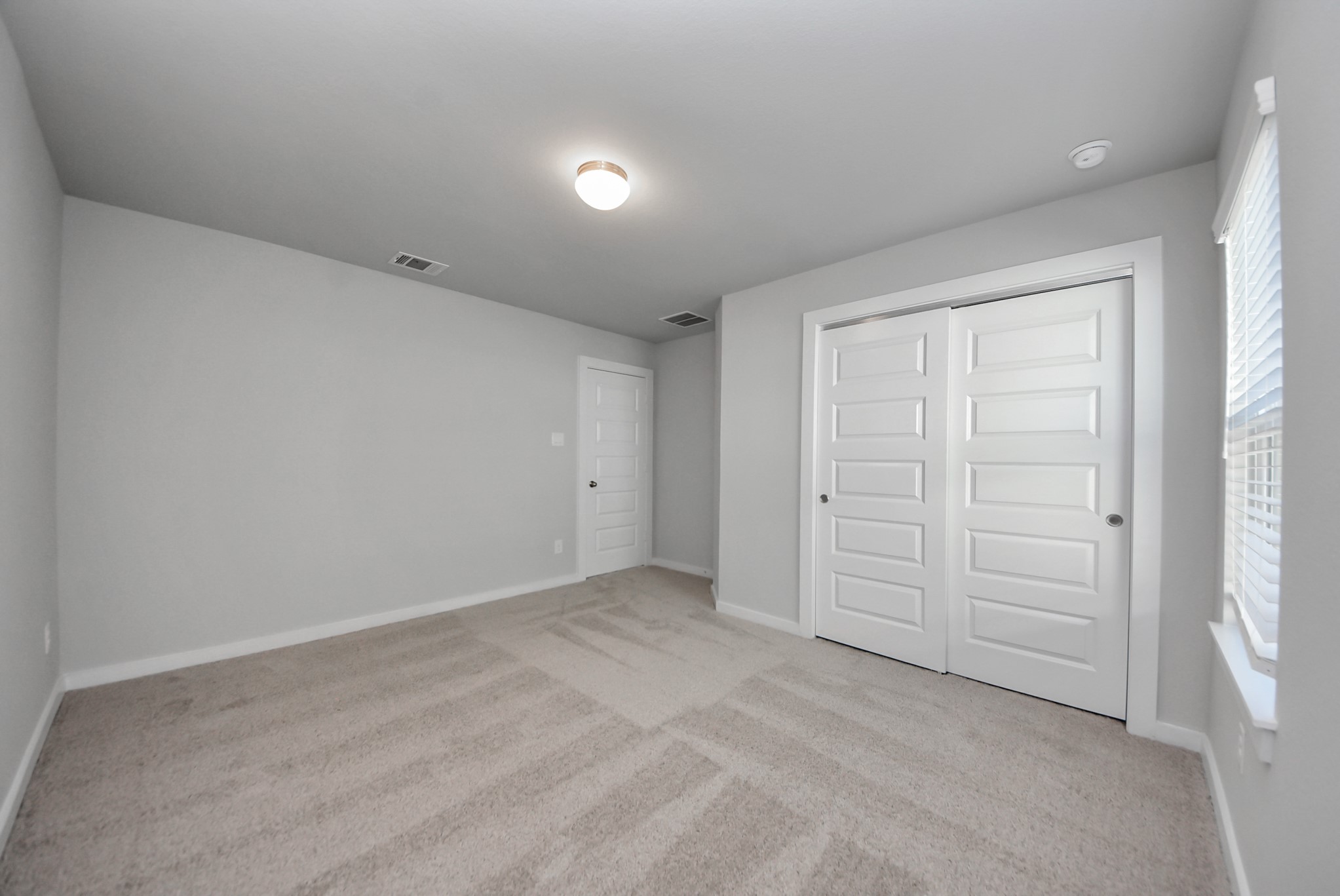 Secondary bedroom features plush carpeting, large windows that let in plenty of natural light, bright paint, and spacious closets.