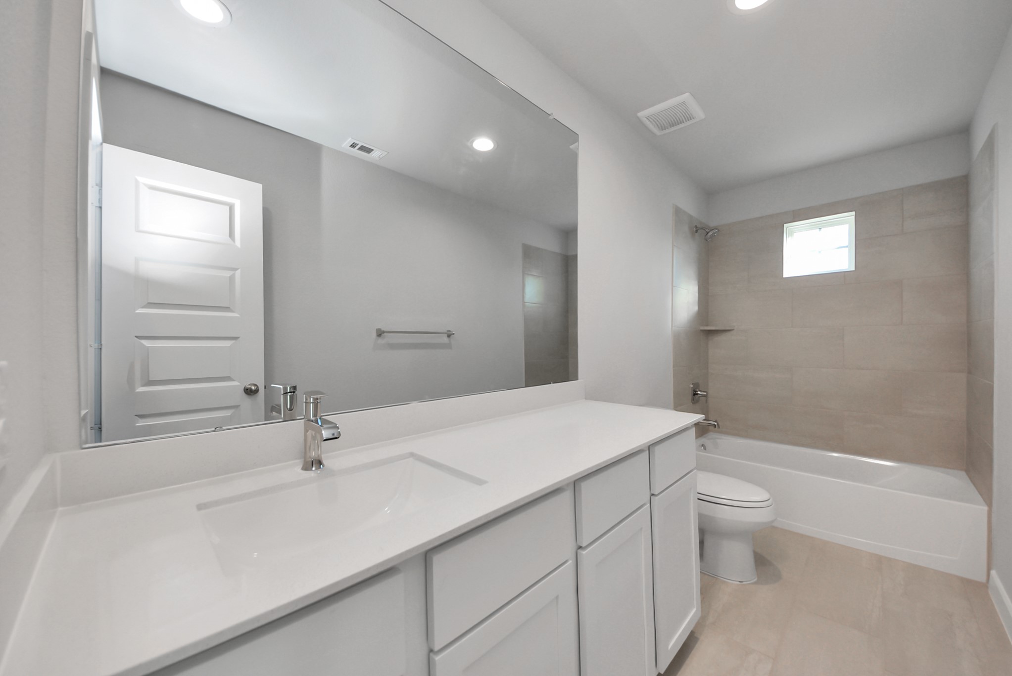 Secondary bath features tile flooring, bath/shower combo with tile surround, light stained wood cabinets, beautiful light countertop.