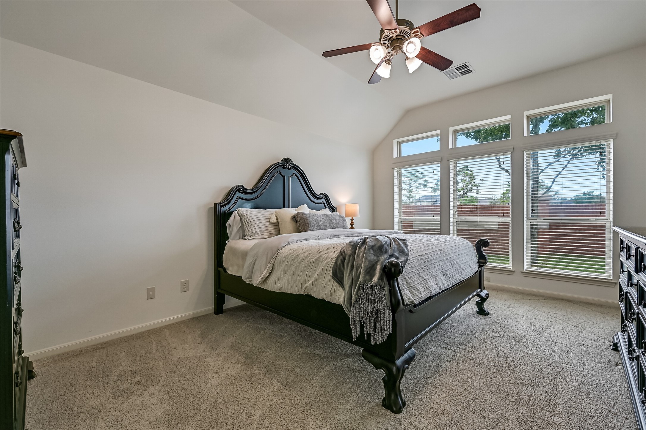 Retreat to this spacious primary suite featuring a soaring ceiling, neutral carpeting, fresh interior paint & a ceiling fan. A dramatic wall of windows with transoms above fills the room with natural light while offering views of the backyard. The adjoining bath features dual vanities, a soaking tub & separate shower.