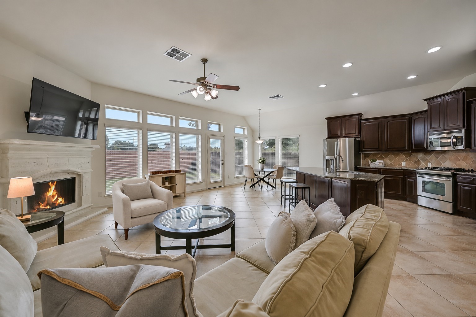 This stunning open-concept living space is filled with natural light from a dramatic wall of windows with transoms above! A beautiful cast-stone fireplace anchors the spacious family room, while the adjoining kitchen offers granite counters, rich wood cabinetry & a large breakfast bar for casual dining.