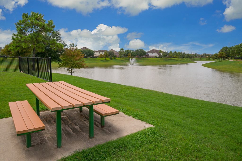 Discover the scenic outdoor spaces throughout Shadow Creek Ranch! This peaceful lakeside setting features a picnic table overlooking a picturesque pond with a fountain, surrounded by beautifully maintained lawns & mature landscaping. A lovely spot to enjoy a picnic, relax outdoors or take in the neighborhood scenery.