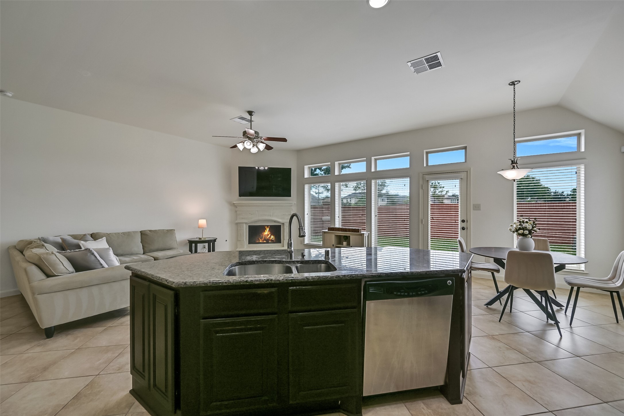 Designed with functionality in mind, this kitchen offers extensive cabinetry, granite countertops & a stainless steel gas range beneath a built-in microwave. A decorative tile backsplash adds warmth, while recessed lighting illuminates the workspace. A nearby pantry provides additional storage.