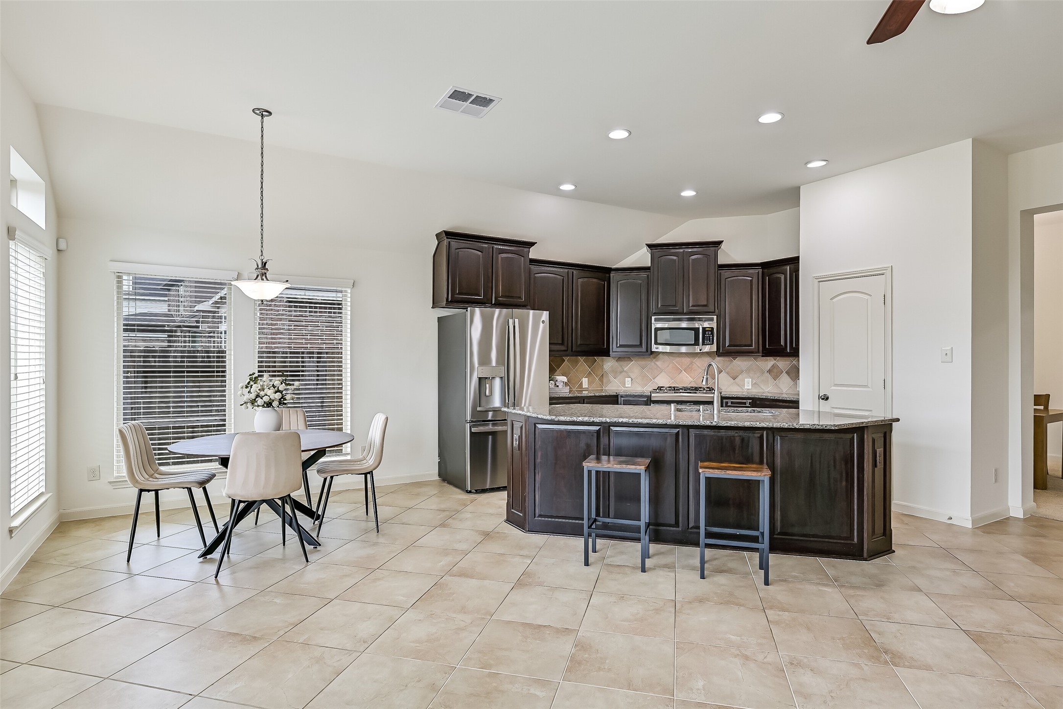 The open kitchen overlooks the spacious family room & adjoins a cheerful breakfast area surrounded by windows! Rich dark-stained cabinetry contrasts beautifully with granite countertops, while an oversized island provides generous workspace & casual seating. Neutral tile flooring unites these inviting spaces.