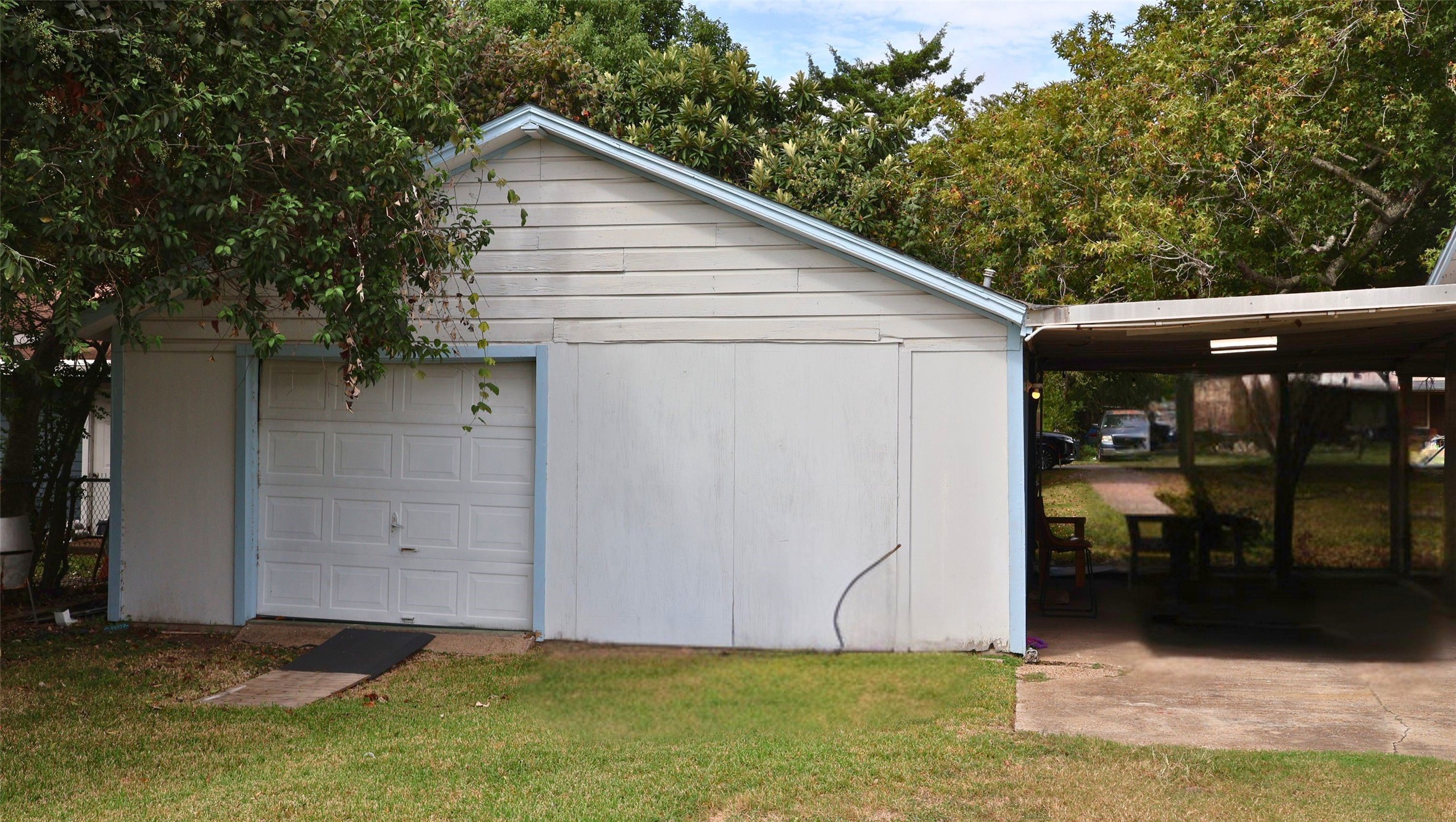 Spacious detached garage with adjacent covered patio area, nestled among mature trees for added shade and privacy.