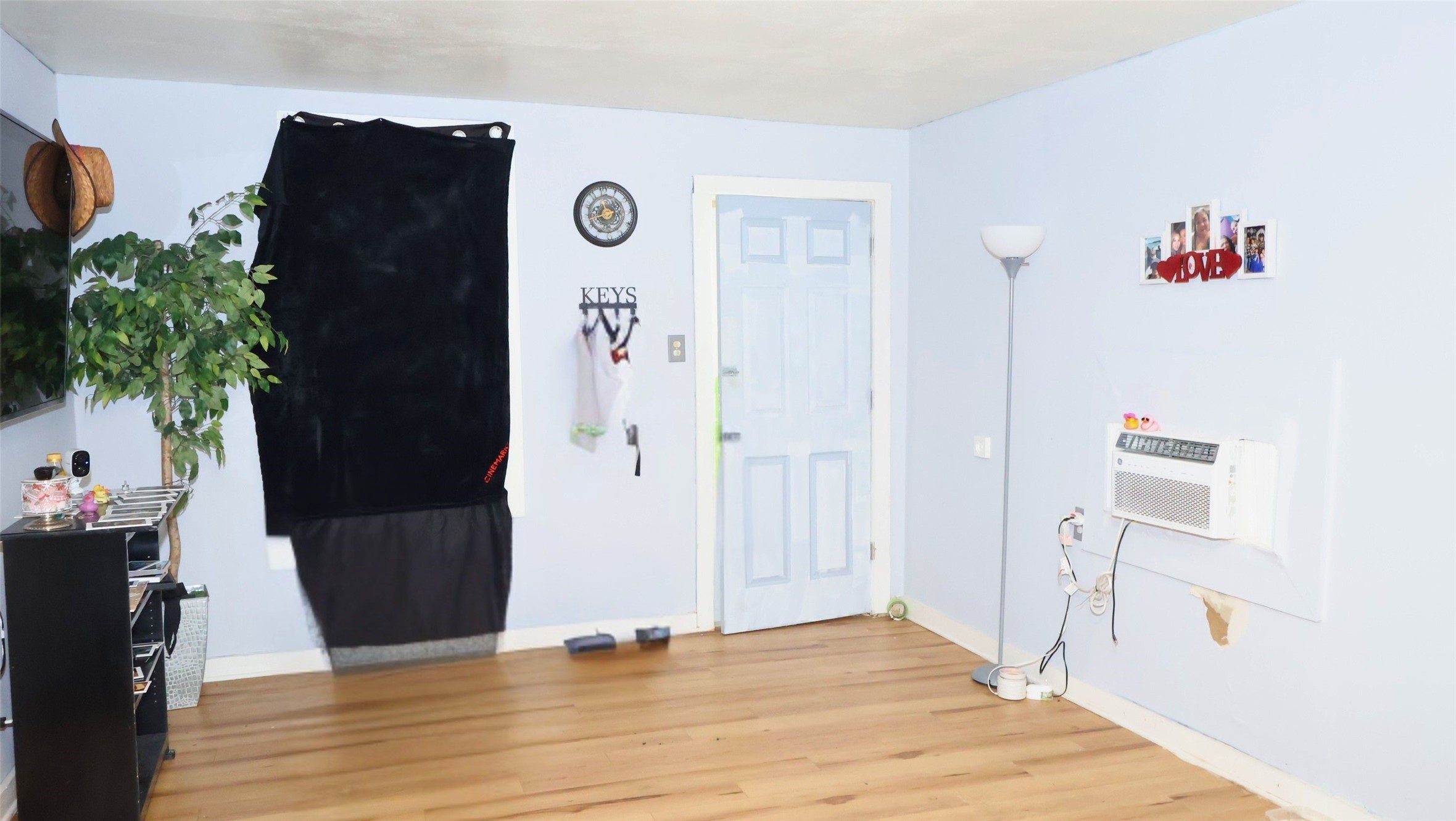Bright and airy room with light blue walls, a wooden floor, and a wall-mounted air conditioner. Features charming, convenient storage solutions. Bright and airy room with light blue walls, a wooden floor, and a wall-mounted air conditioner. Features charming, convenient storage solutions.
