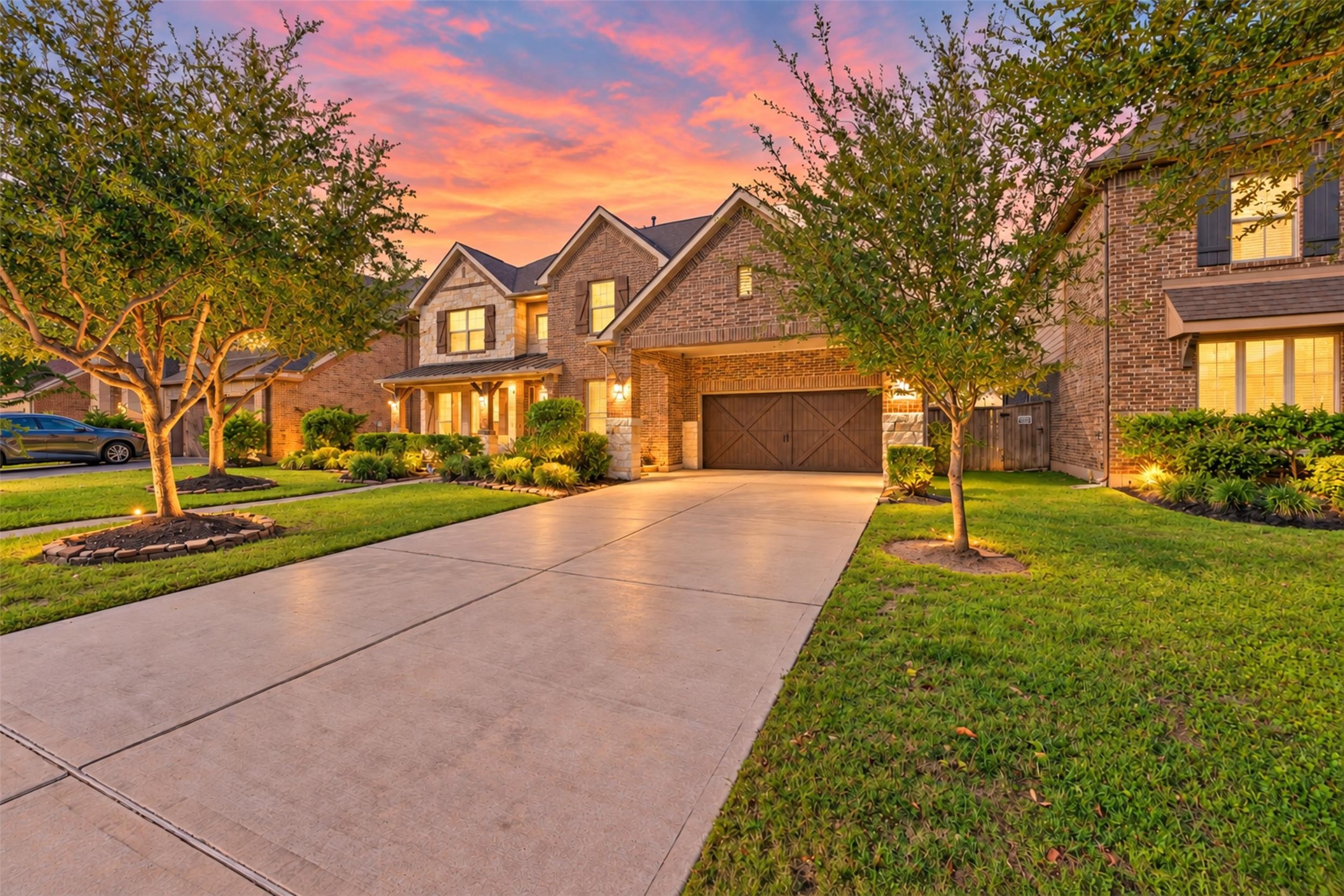 This absolutely gorgeous Lennar home in Cinco Ranch Northwest knows how to make a stunning first impression! The striking brick and stone exterior, upgraded cedar garage doors, manicured landscaping, and inviting evening glow create exceptional curb appeal.