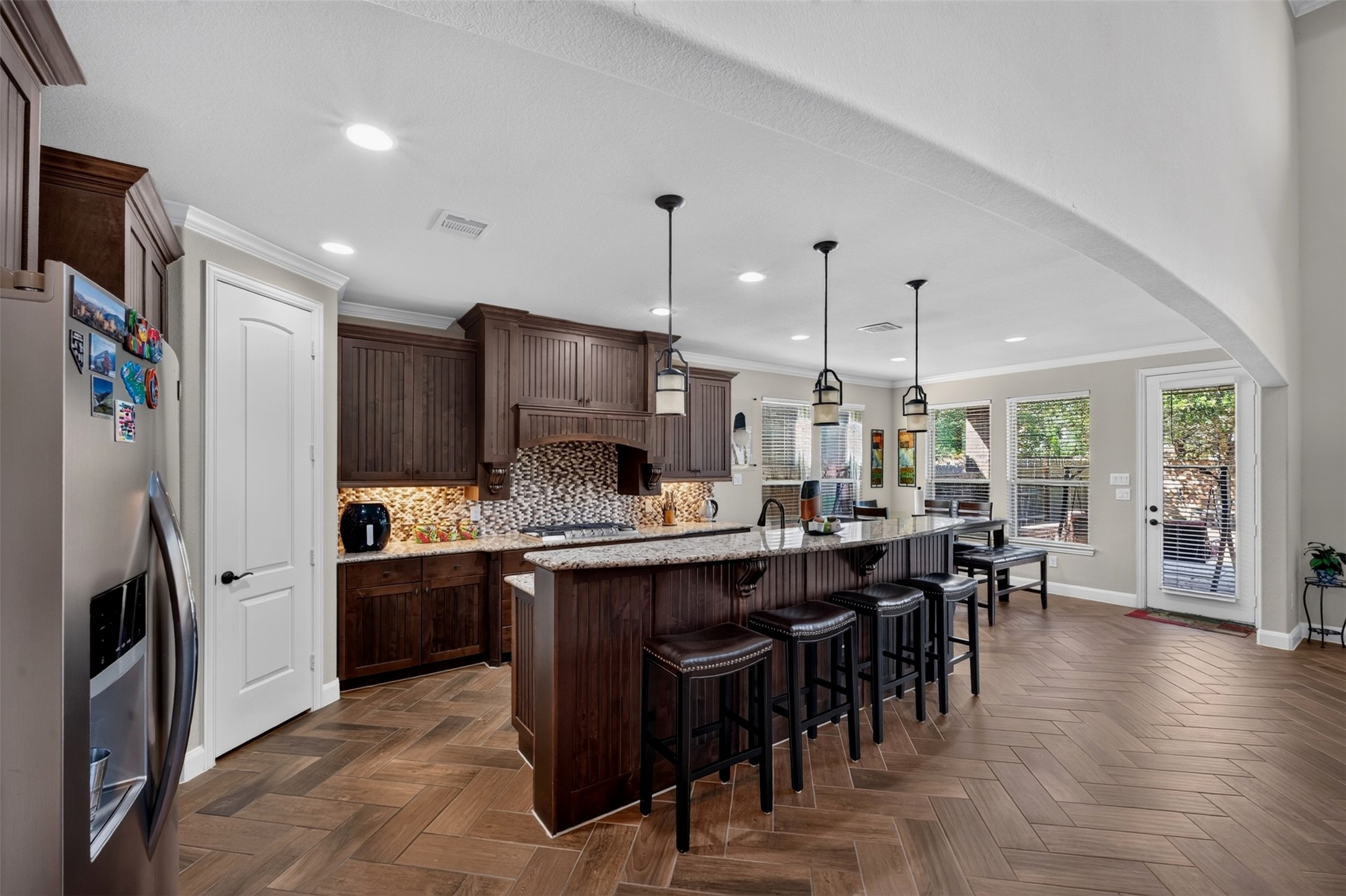 The kitchen opens into a bright dining area, creating a natural gathering place for busy mornings and casual meals. Rich maple cabinetry, granite countertops, pendant lighting, and abundant windows give this space both warmth and functionality.