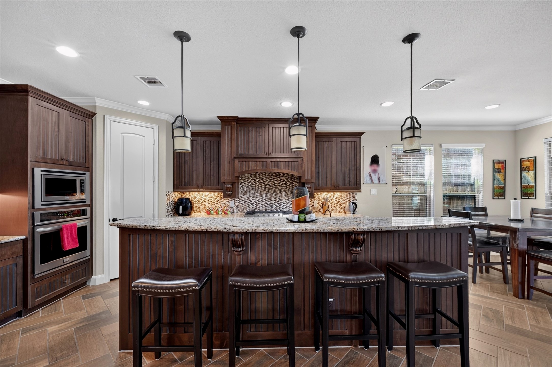The expansive island takes center stage, offering generous countertop space for meal preparation, serving, and conversation. Bar seating makes it easy for guests to gather nearby while the cook puts the finishing touches on dinner.