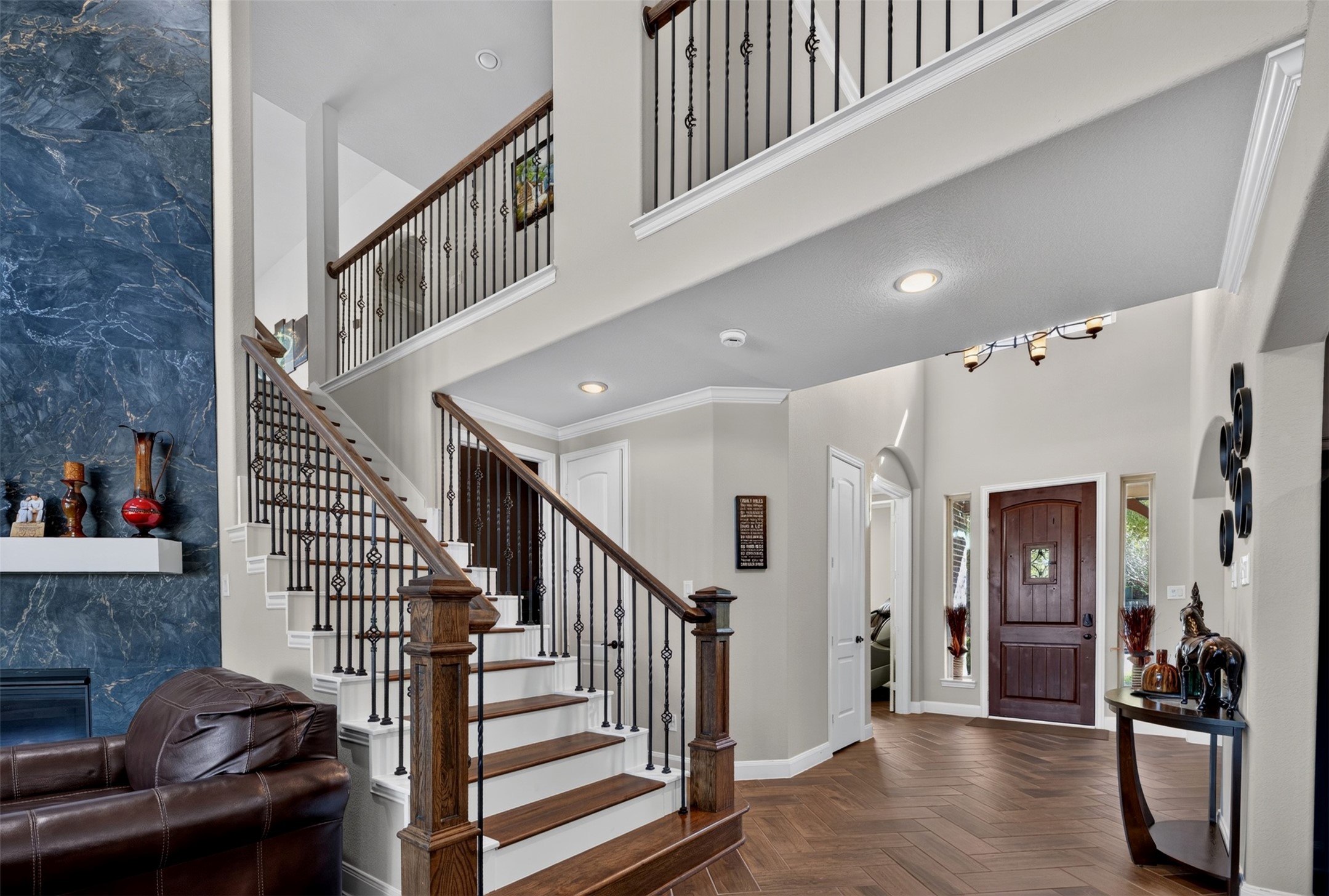 Returning to the main living area, the staircase makes a striking impression with dark wood treads, substantial wood handrails, and decorative wrought-iron balusters.