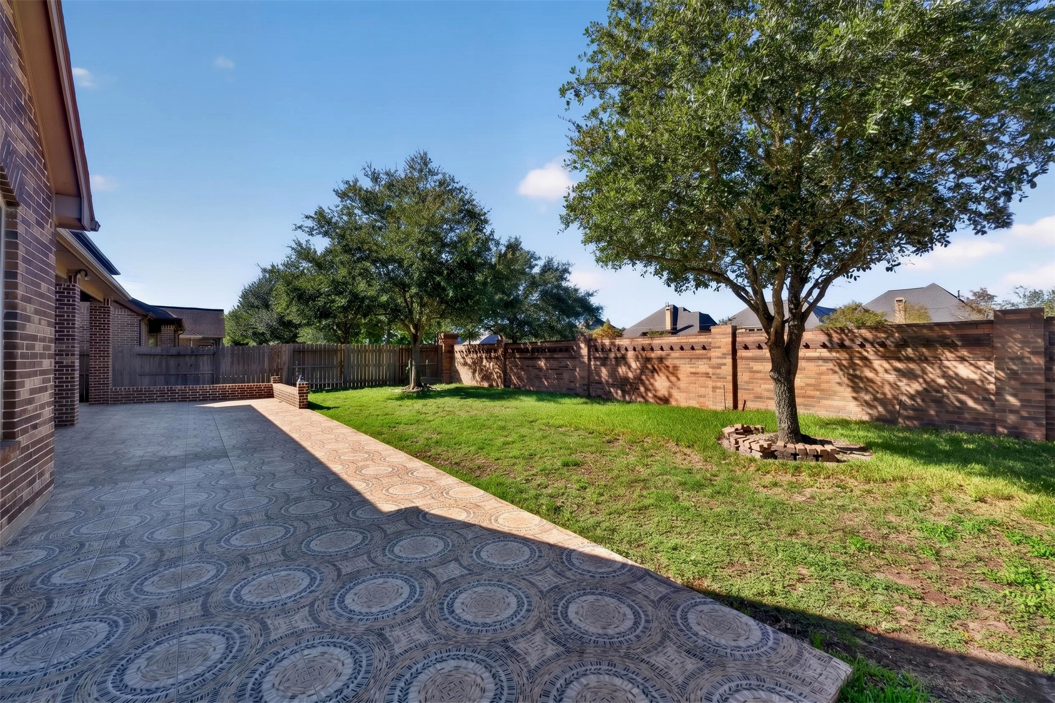The low maintenance backyard offers a generous lawn framed by mature trees.