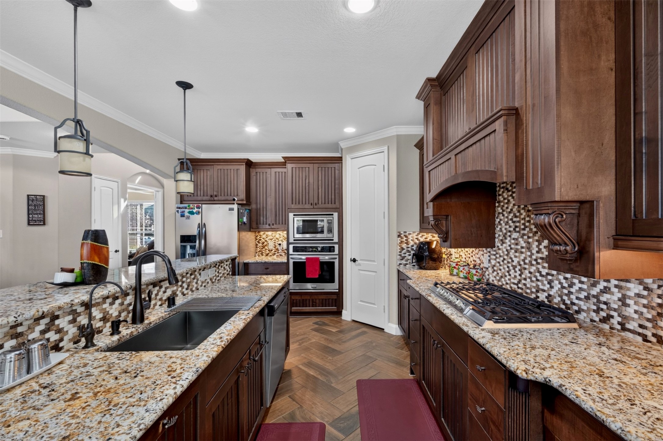 A closer look reveals the kitchen's thoughtful details, including granite countertops, a decorative mosaic backsplash, rich cabinetry, and a stainless-steel sink. The generous work surfaces provide plenty of room to prepare meals while keeping everything within reach.