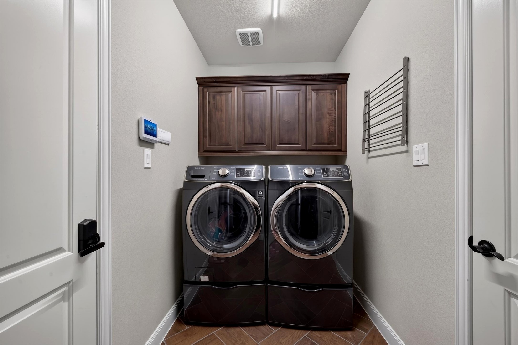 Even everyday chores feel more organized in this dedicated utility room. Front-loading washer and dryer units sit beneath built-in cabinetry, providing convenient storage and a neat, functional laundry space.
