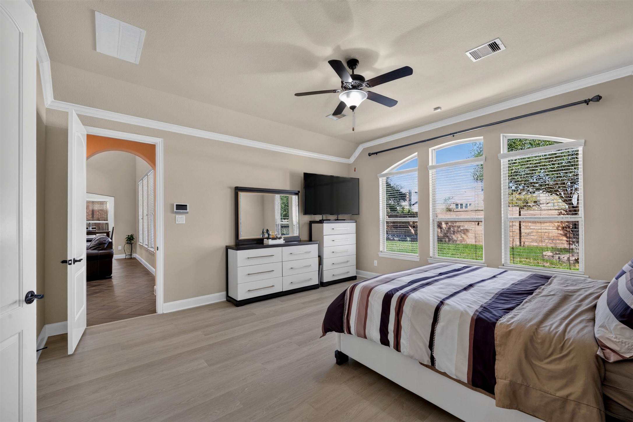 The light wood-look flooring complements the warm wall color while the space offers flexibility for additional furniture.