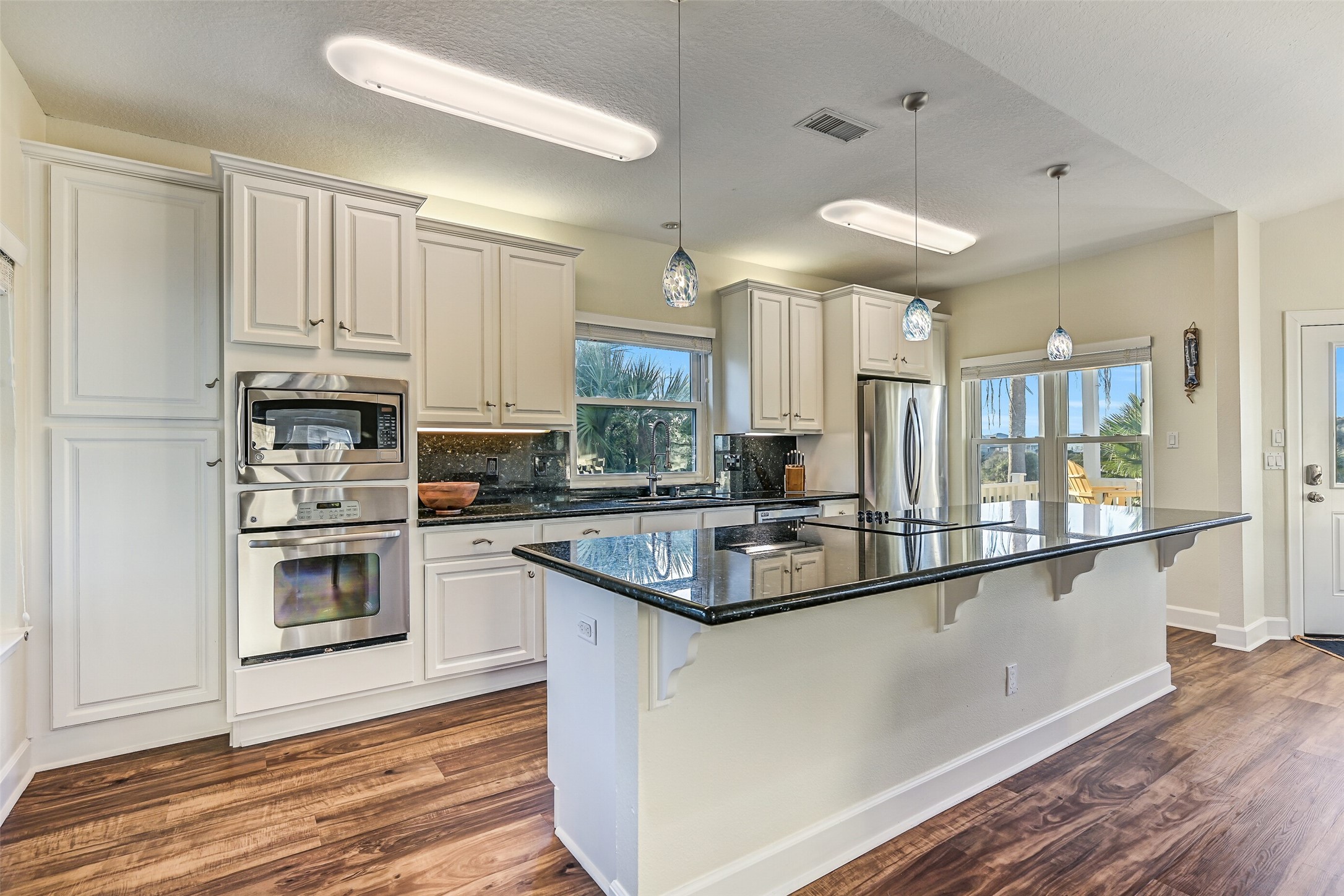Perfect for cooking and entertaining, the kitchen showcases stainless steel appliances, a generous island with electric cooktop, and extensive cabinetry.