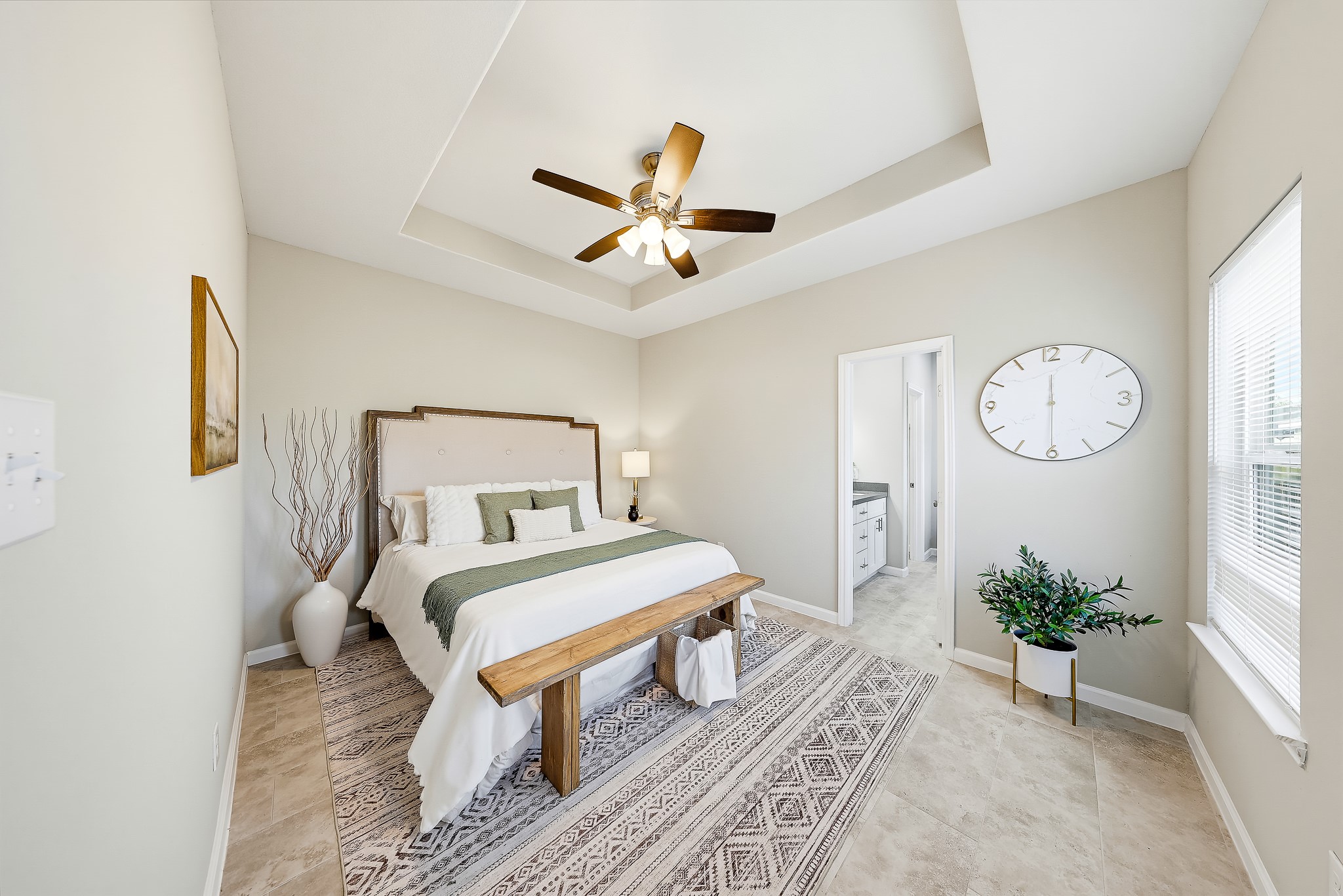 Retreat downstairs to a primary bedroom with soft natural light and a distinctive tray ceiling.